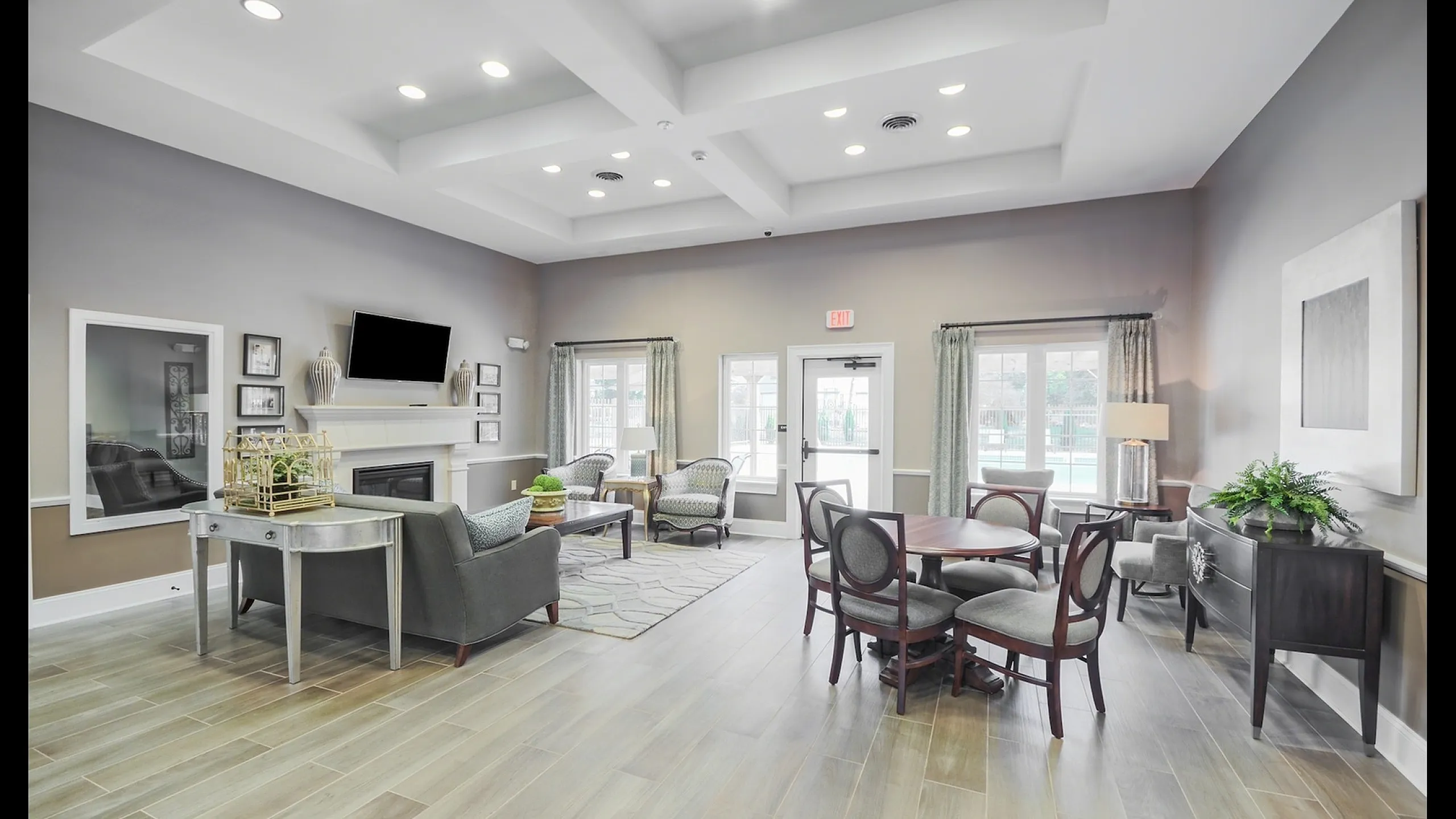 Elegant and spacious living area with modern furnishings, featuring a cozy fireplace, stylish seating, and abundant natural light through large windows.