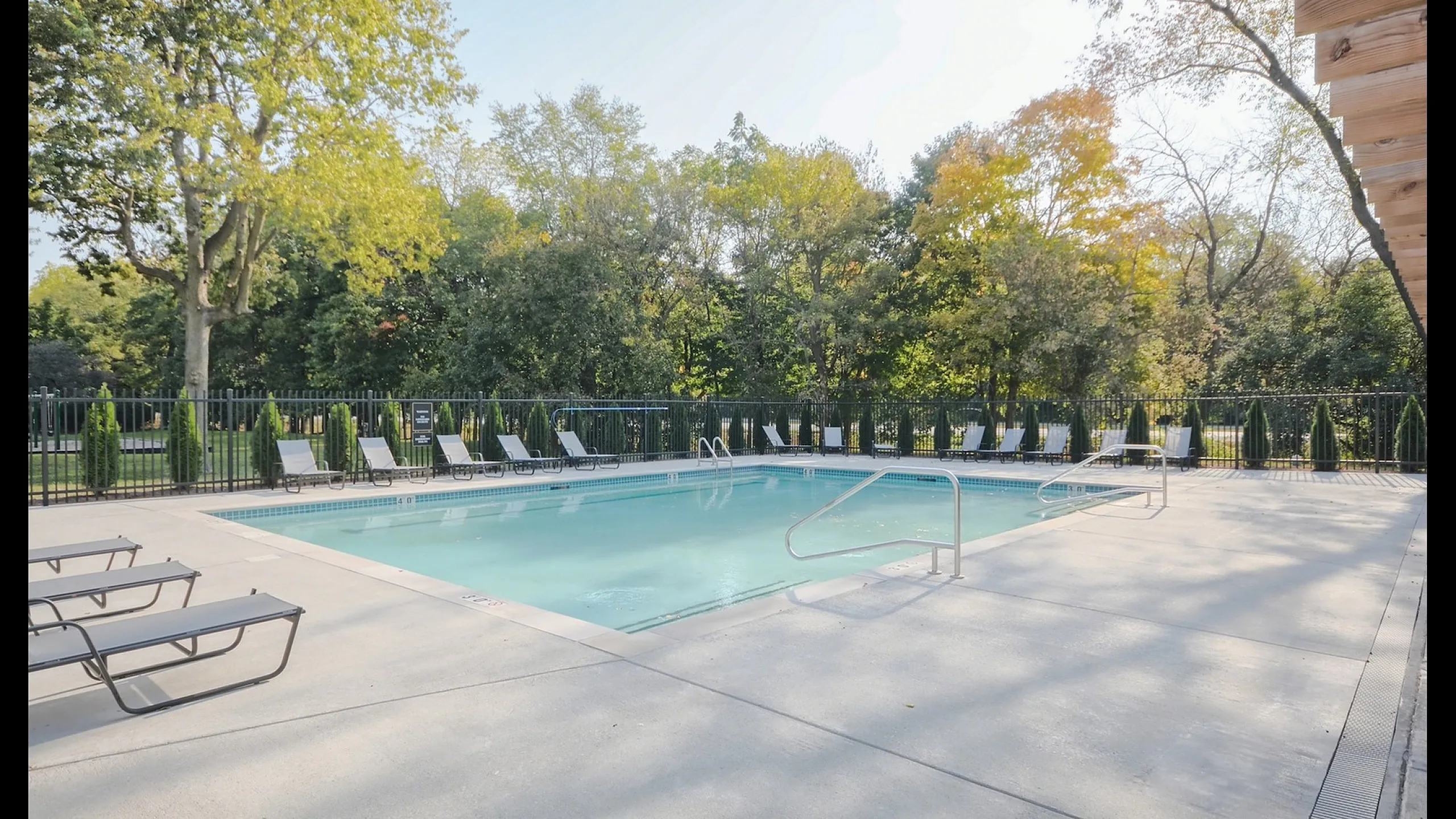 Inviting outdoor pool area surrounded by lush greenery and comfortable sun loungers, perfect for relaxation and leisure.