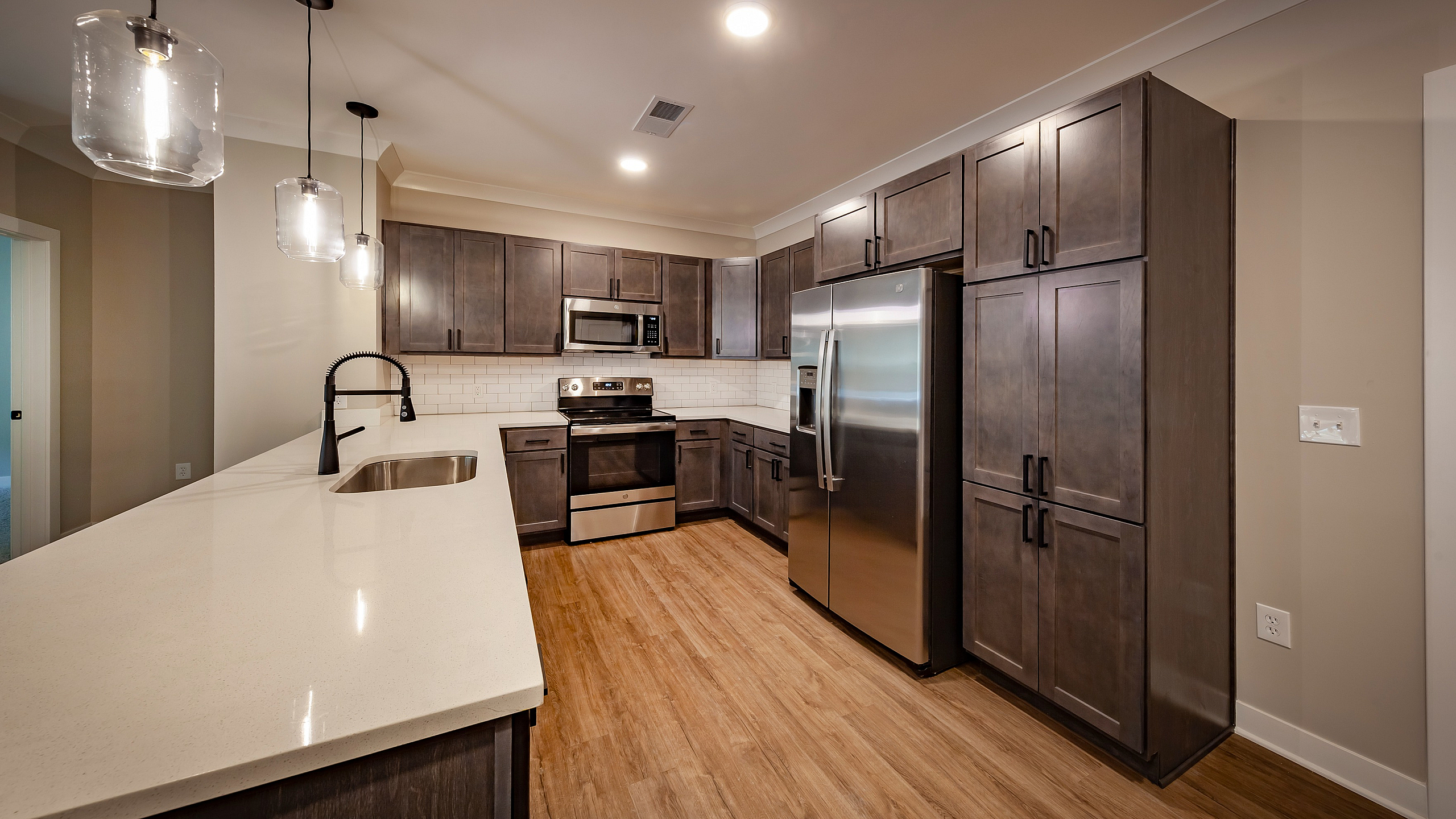 Modern kitchen with sleek stainless steel appliances, elegant dark cabinetry, and stylish pendant lighting.