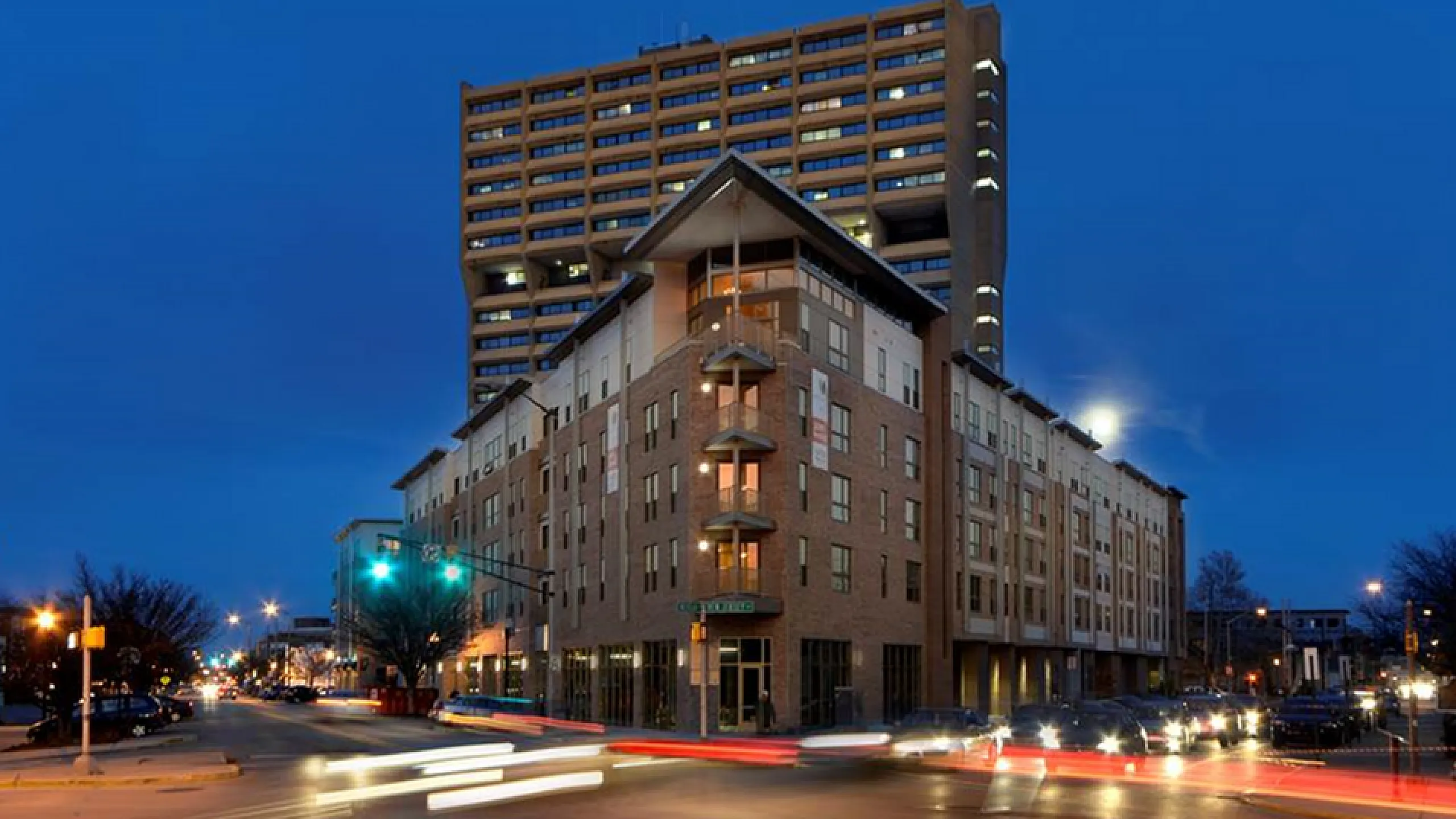 Elegant urban apartment complex illuminated against a vibrant evening sky, showcasing modern architecture and city allure.