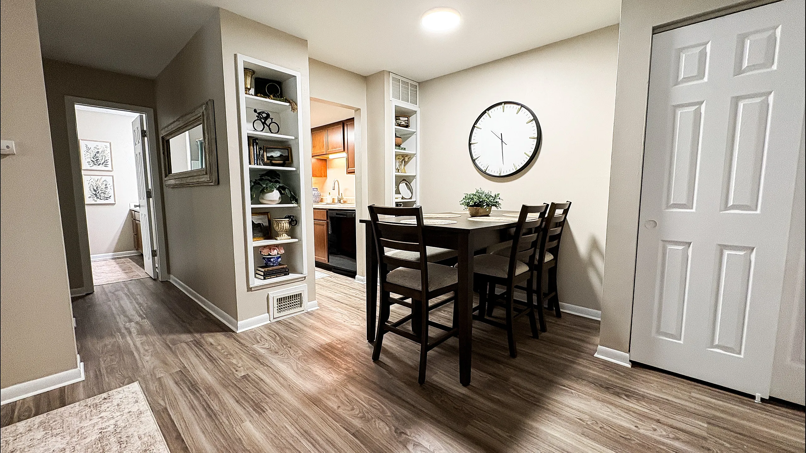 Inviting dining area with modern wooden flooring, a chic table set, and stylish wall shelves, opening to a cozy kitchen at Main Street on the Monon