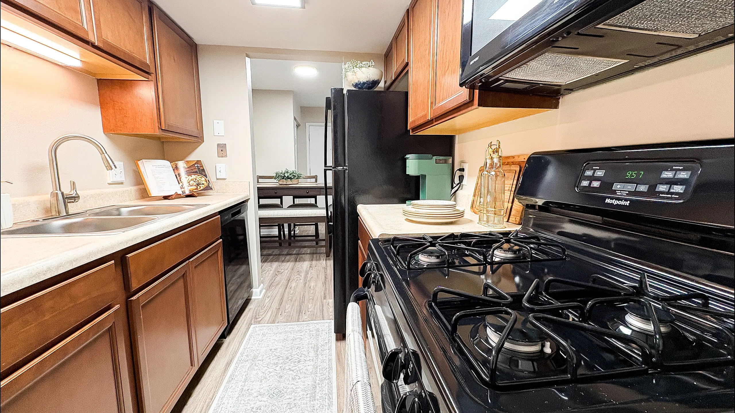 Inviting kitchen with sleek black appliances, warm wood cabinetry, and elegant countertops leading to a charming dining area.