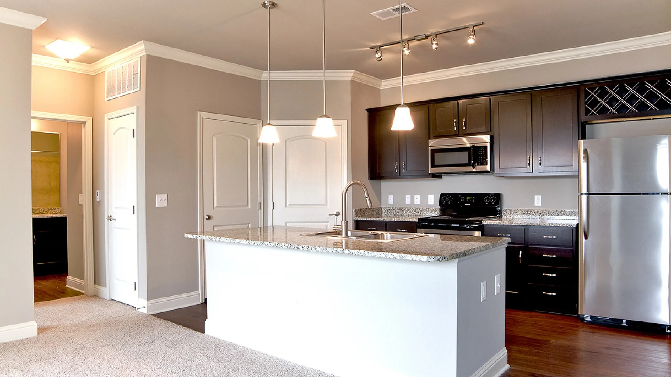 Modern kitchen with elegant dark cabinetry, stainless steel appliances, and a sleek granite countertop island with pendant lighting.