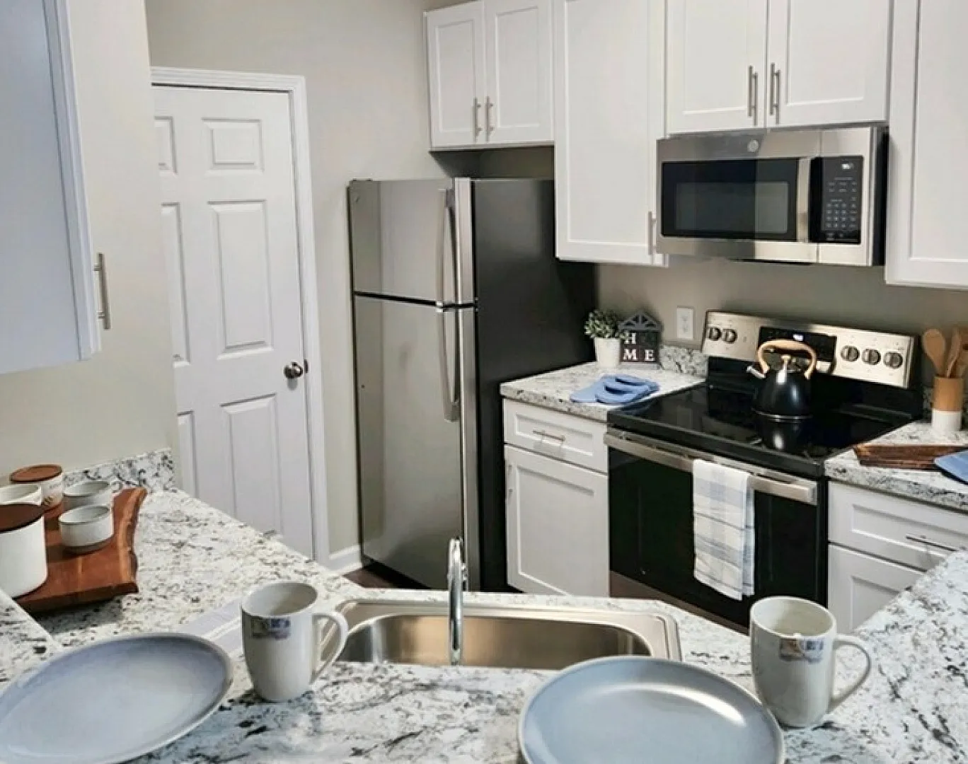 Elegant modern kitchen with sleek granite countertops, stainless steel appliances, and white cabinetry, perfect for culinary enthusiasts.