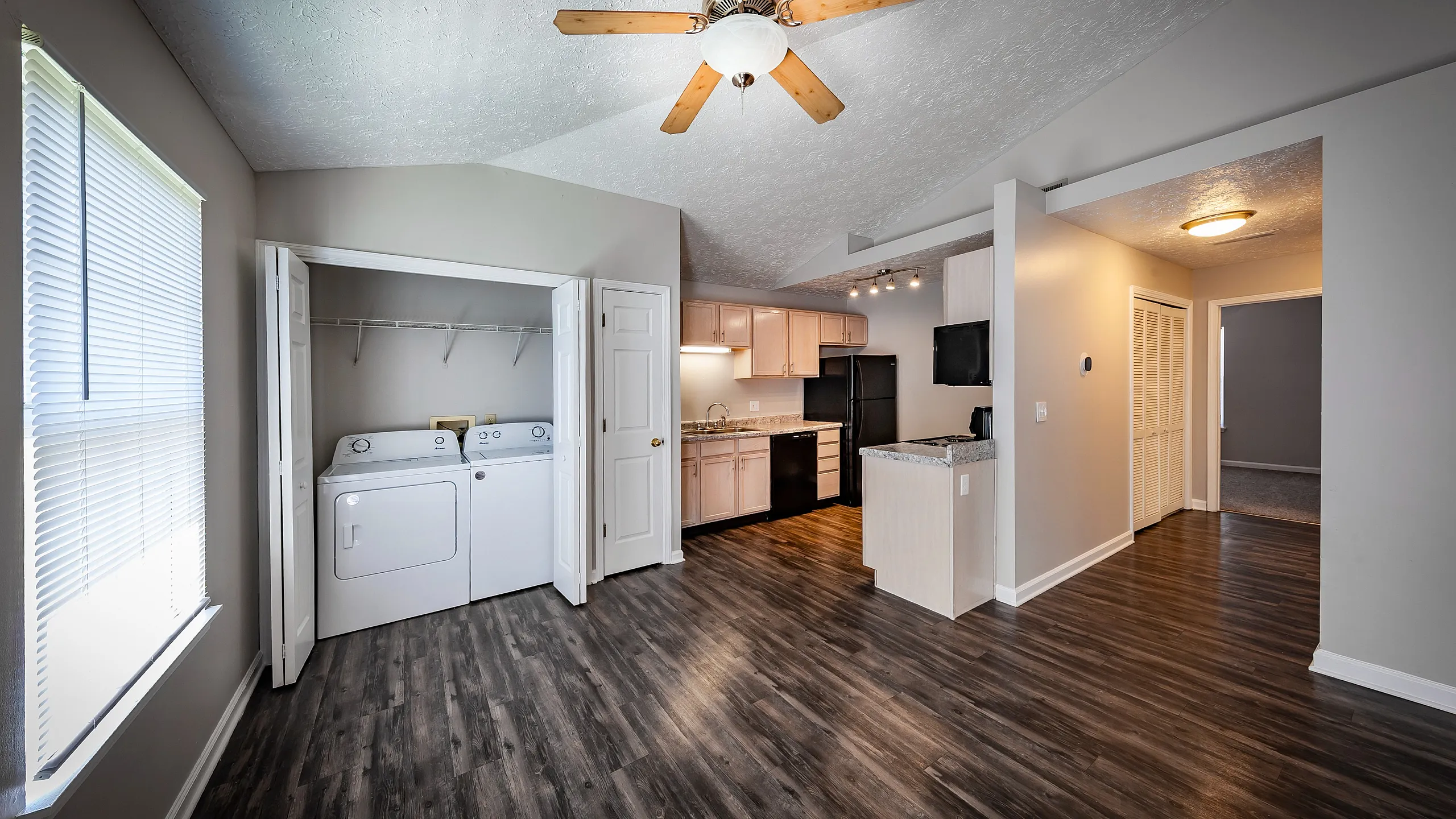 Modern apartment featuring an open-concept kitchen with sleek cabinetry, elegant flooring, and an in-unit laundry area.