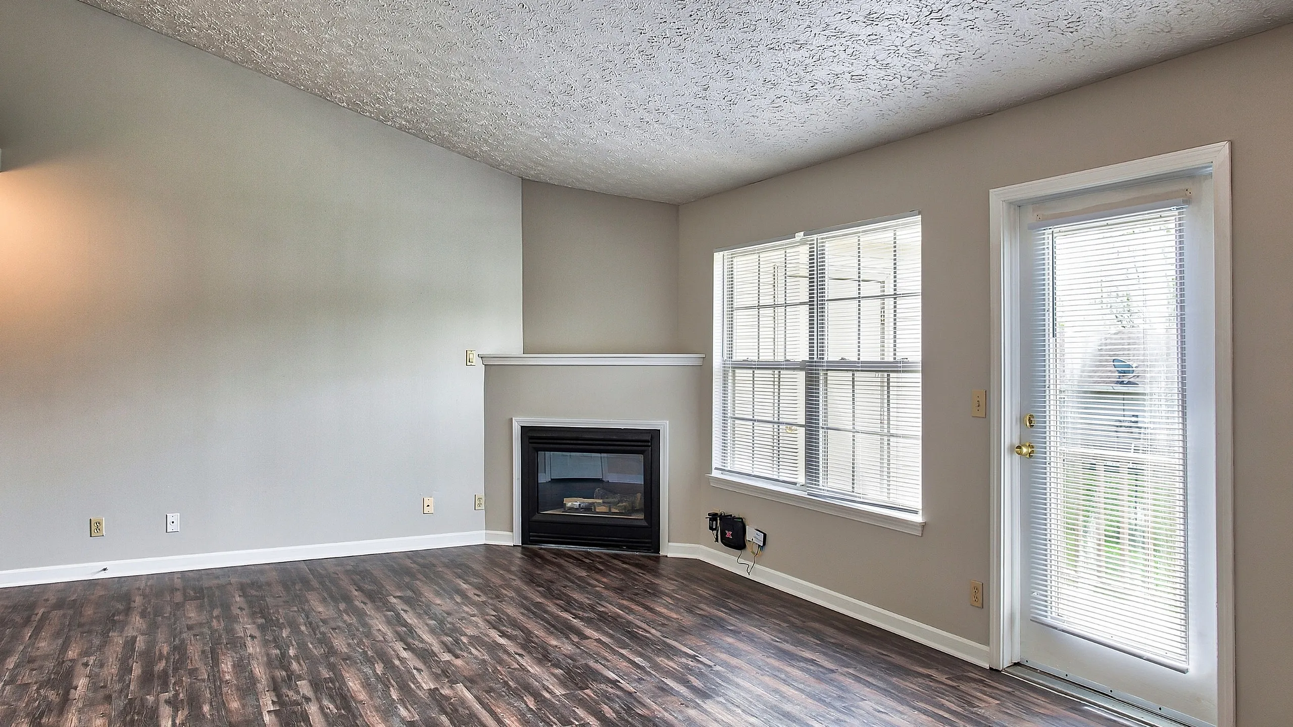 Bright and spacious living room featuring elegant wood flooring, a cozy fireplace, and large windows for natural light.