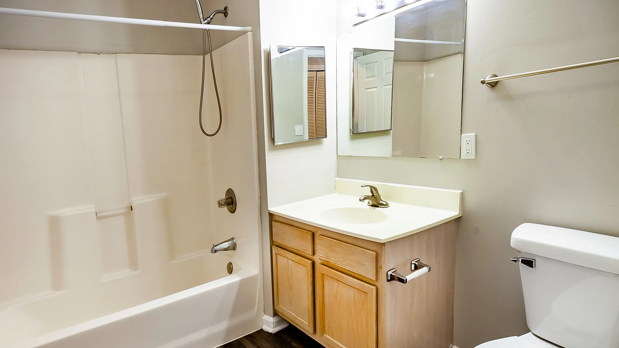 Modern bathroom with elegant wood flooring, a sleek vanity, and a spacious bathtub.