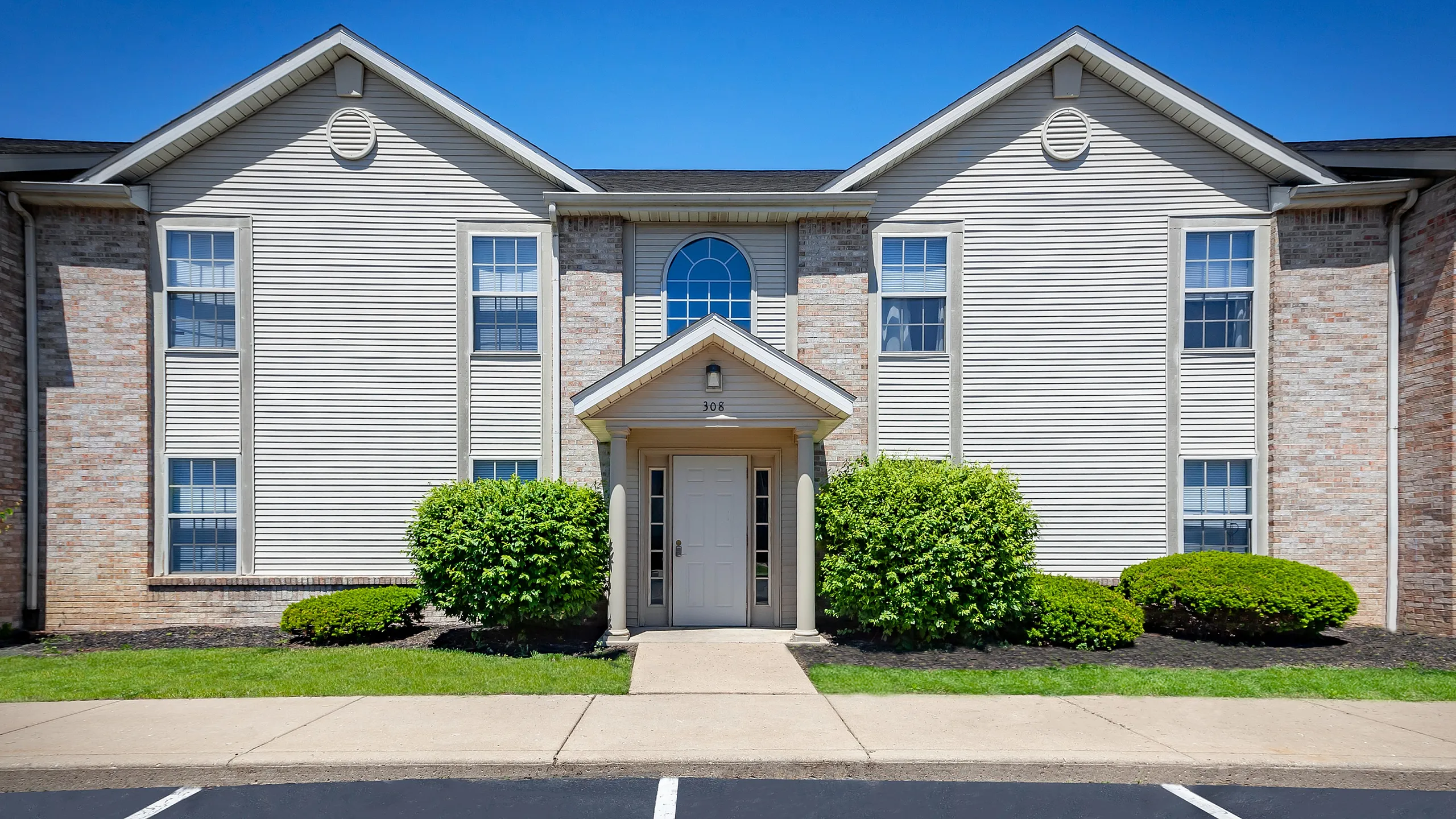 Charming apartment building with classic brick facade and lush greenery, offering a warm and inviting entrance.