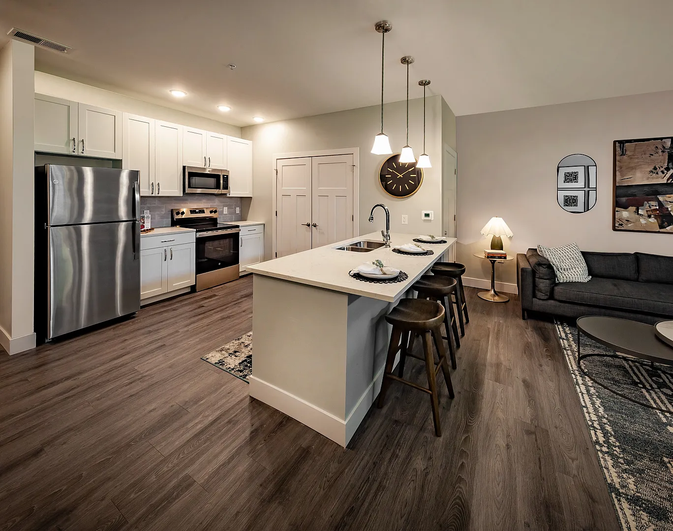 Modern open-concept kitchen and living room with sleek stainless steel appliances, stylish bar seating, and chic decor.