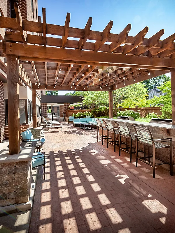 Charming outdoor patio with wooden pergola, cozy seating, and lush greenery, perfect for entertaining or relaxing.