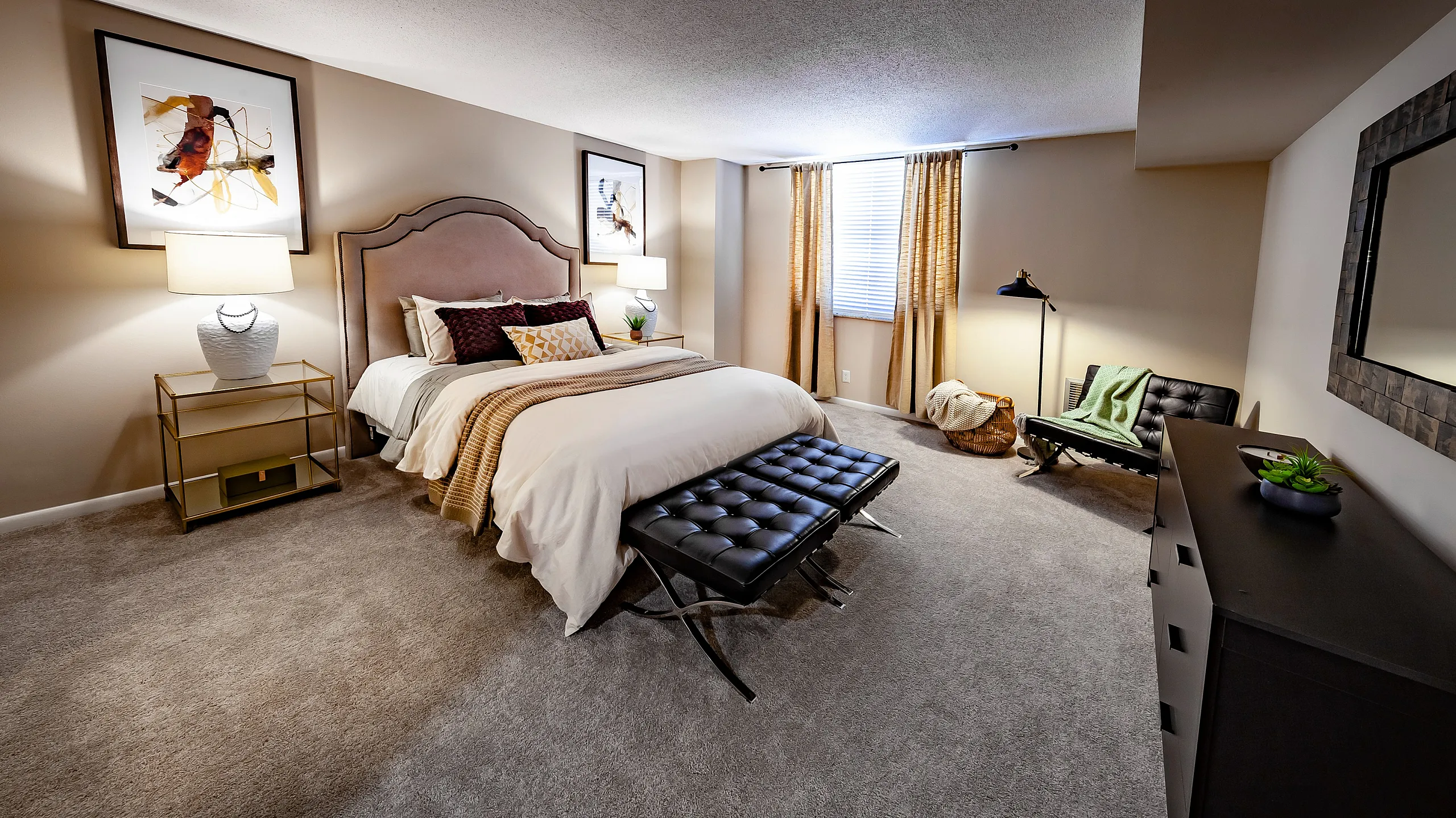 Inviting bedroom with plush carpet, elegant queen bed, artistic decor, and abundant natural light.
