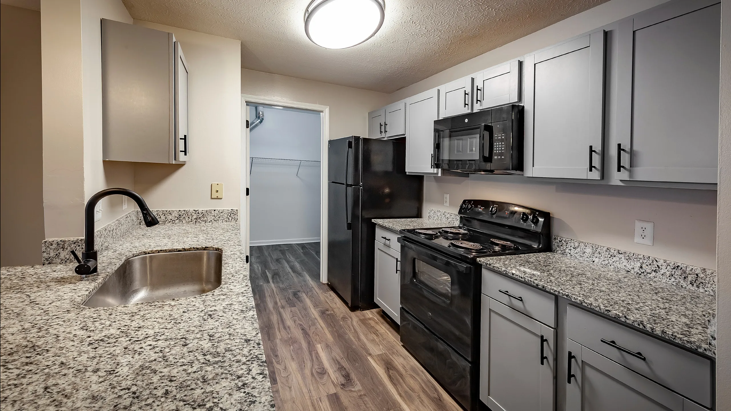 Modern kitchen with sleek gray cabinetry, granite countertops, and stainless steel sink, offering a sophisticated cooking space.