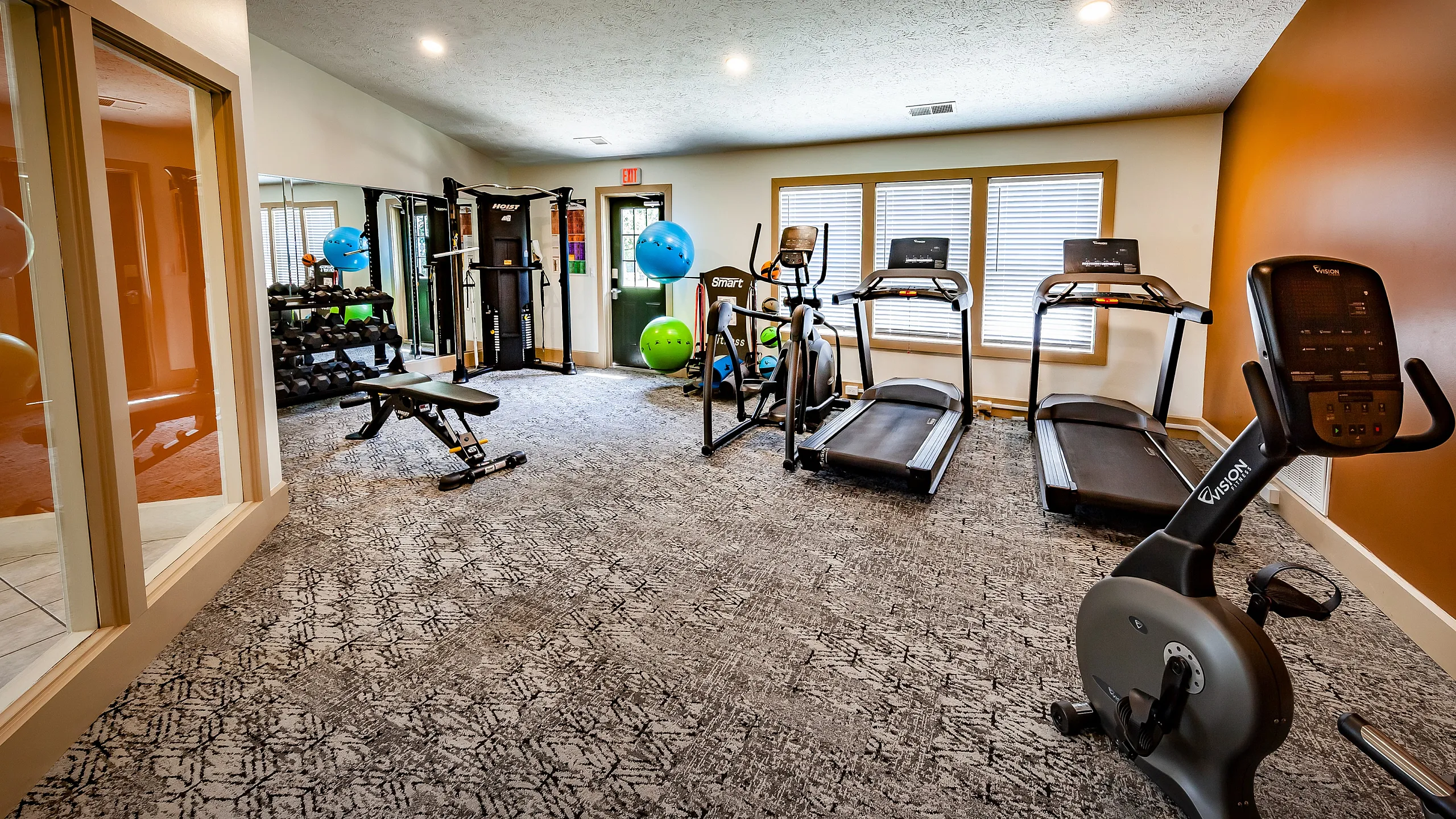 Inviting fitness center equipped with modern treadmills, exercise bike, and strength training equipment under soft lighting.