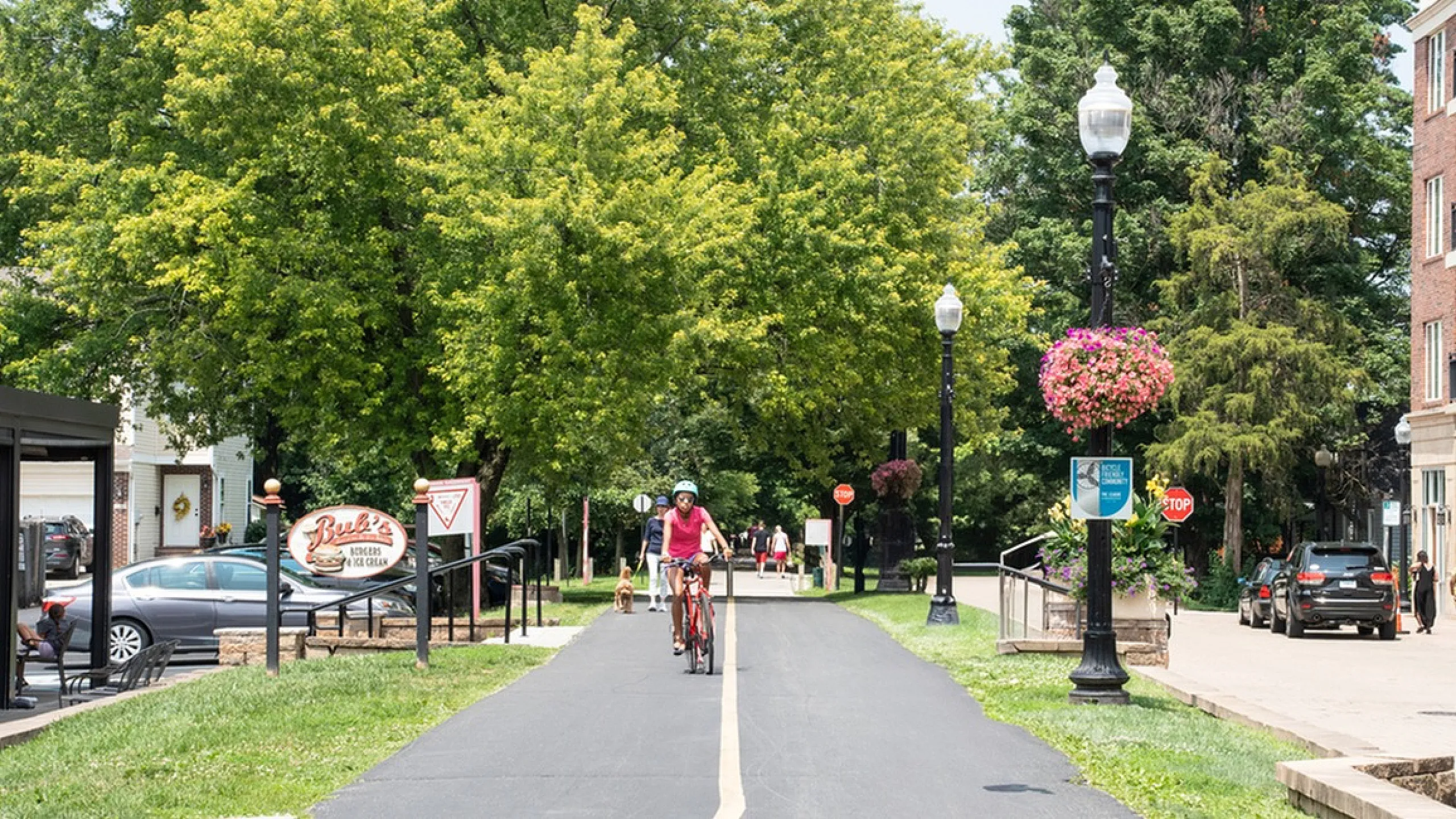 Old Town on the Monon Charming suburban bike path lined with lush trees and vibrant hanging flowers, perfect for a scenic ride.