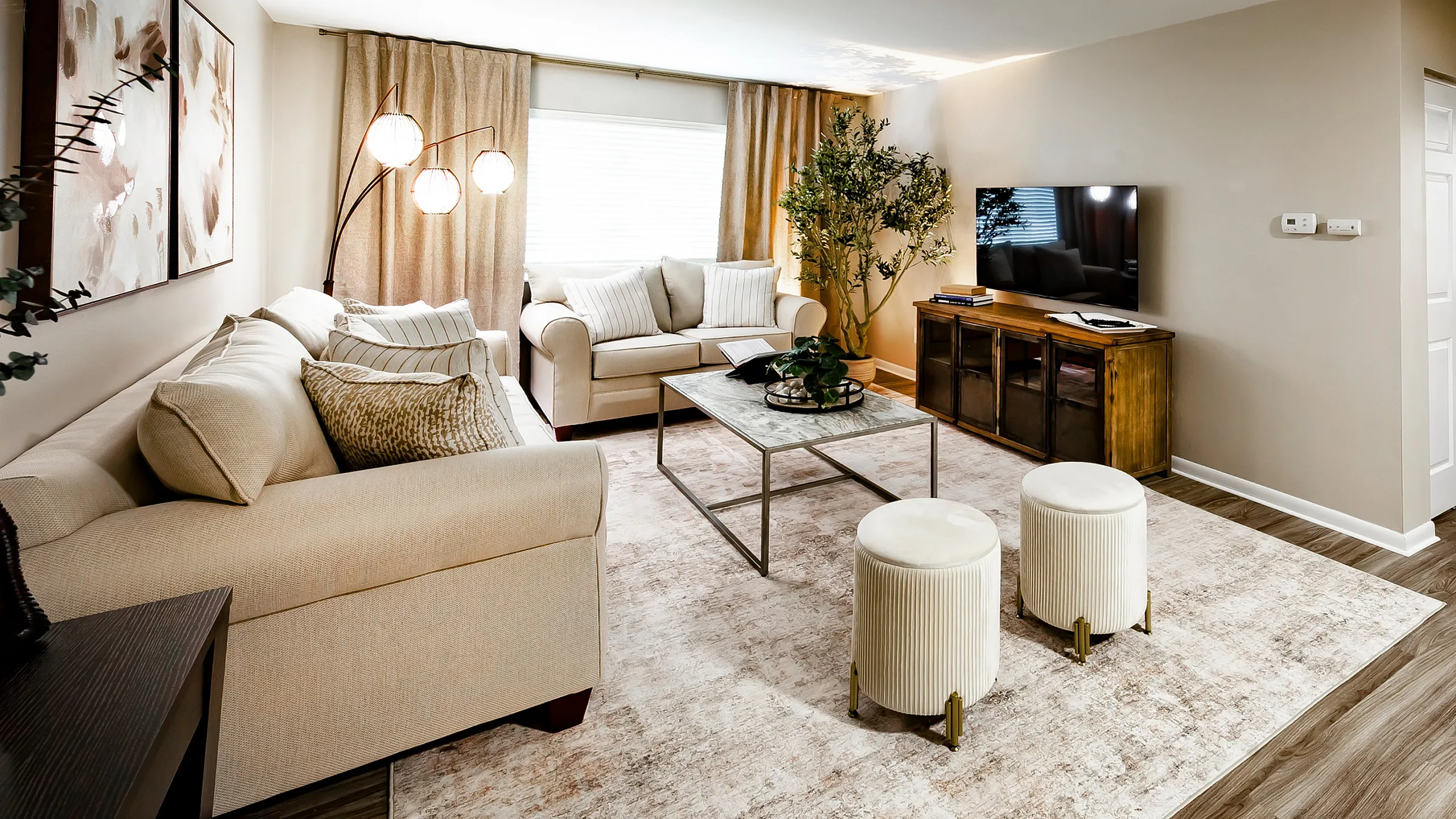 Main Street on the Monon Apartment - Inviting living room with elegant beige sofas, stylish coffee table, and modern decor on a chic area rug.