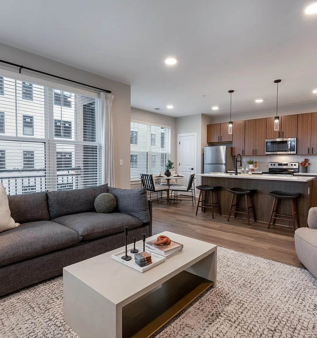 Modern open-concept living area with spacious kitchen and cozy seating, showcasing stylish design and ample natural light.