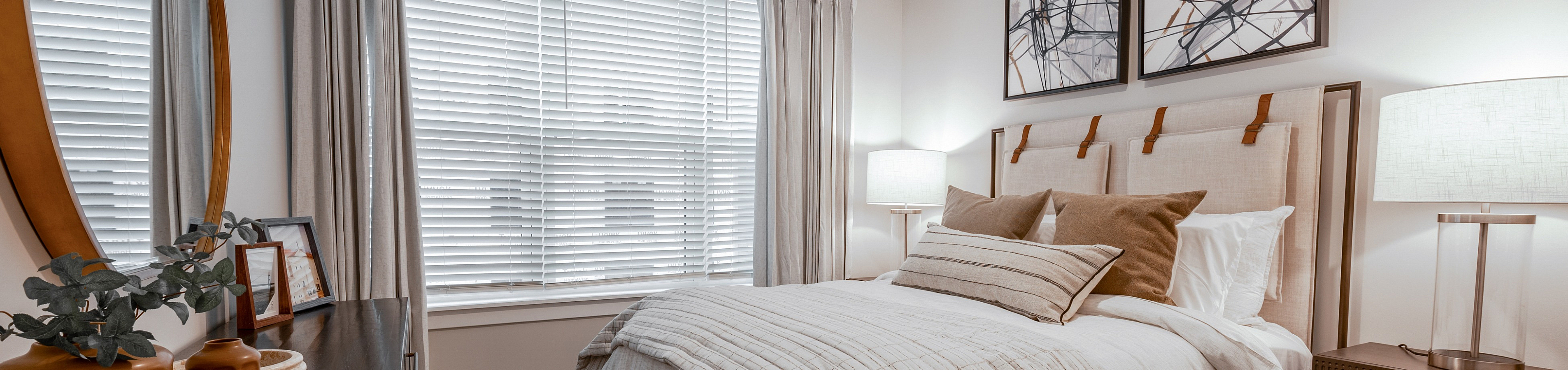 Elegant bedroom with cozy decor, featuring a queen-sized bed with a padded headboard, stylish artwork, and large window with natural light.