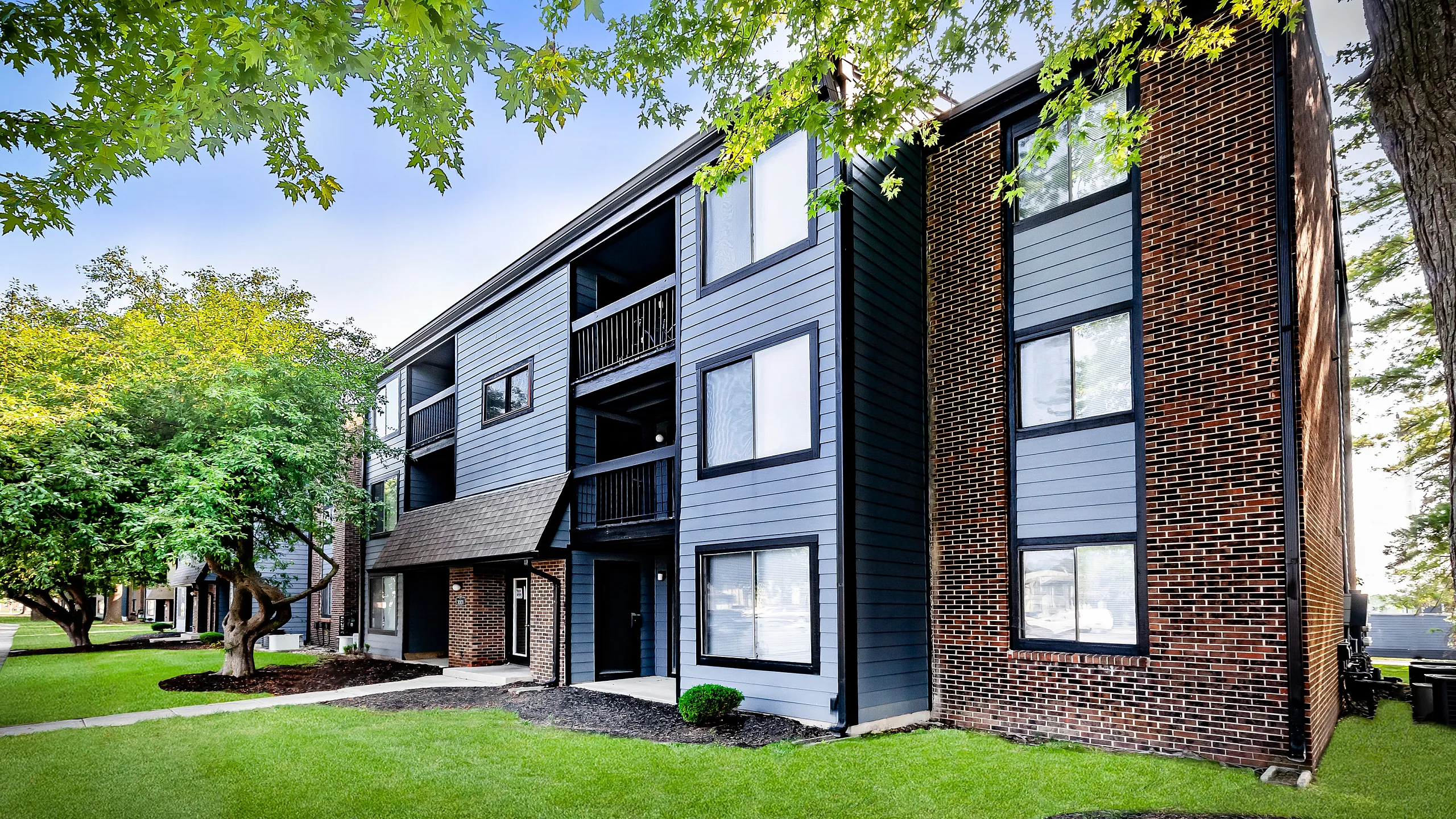 Charming apartment exterior with modern facade and lush landscaping, perfect for comfortable living.