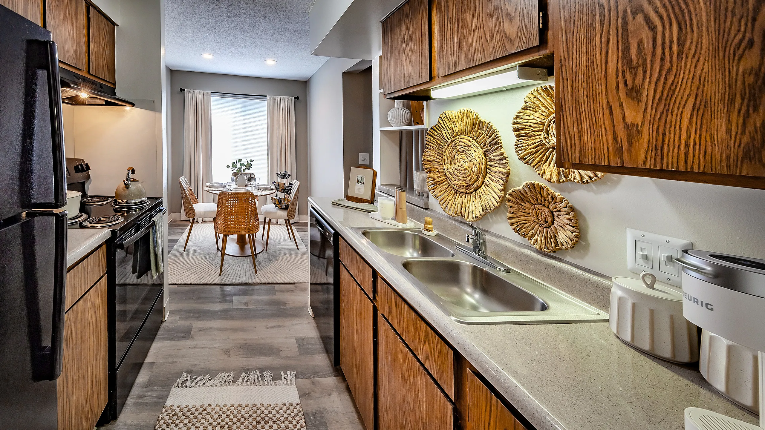 Chic apartment kitchen with elegant wood cabinetry, modern appliances, and stylish dining area featuring natural light and artistic wall decor.
