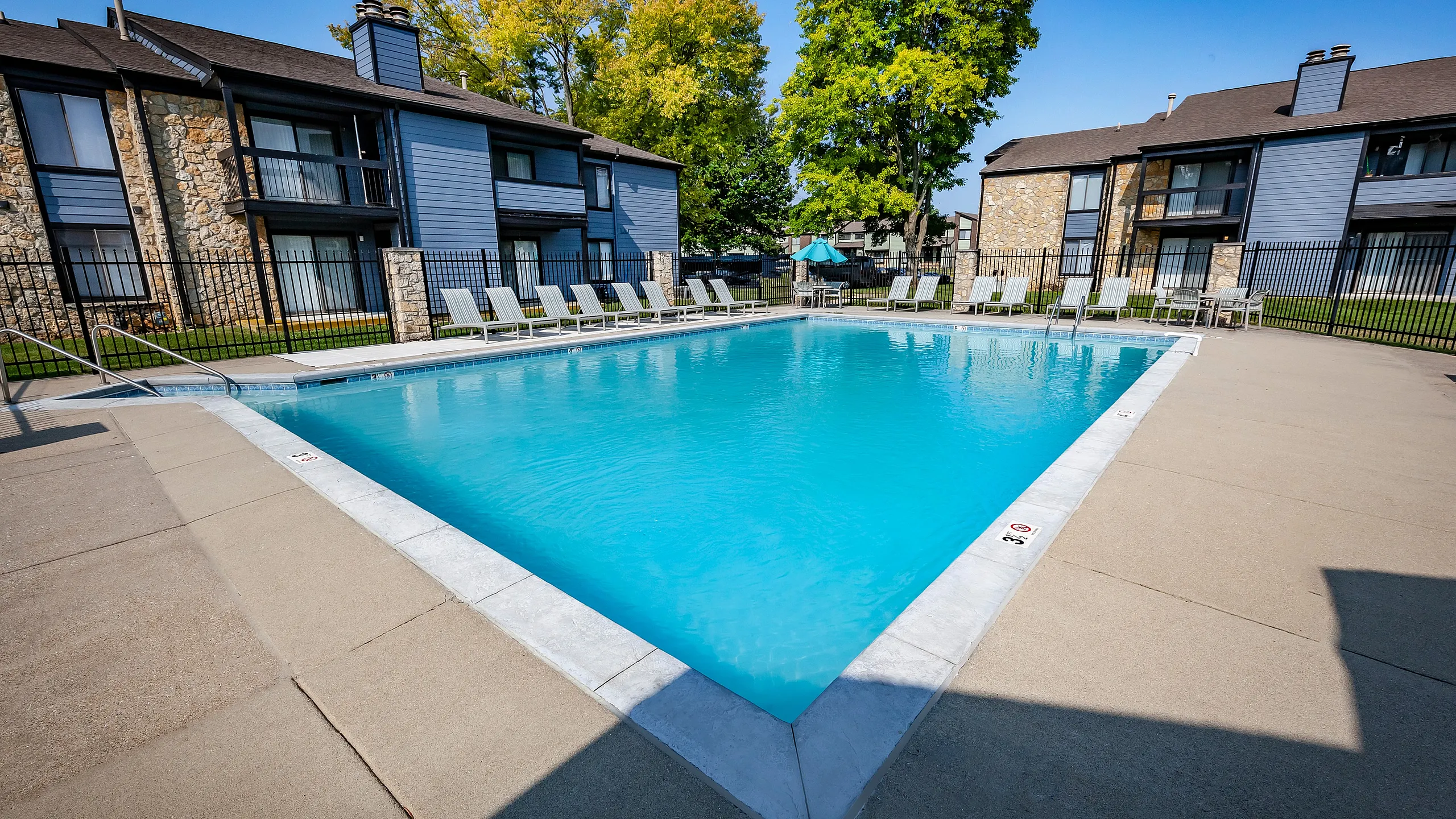 Inviting outdoor pool area with lounge chairs and modern building backdrop, perfect for relaxation and enjoyment.