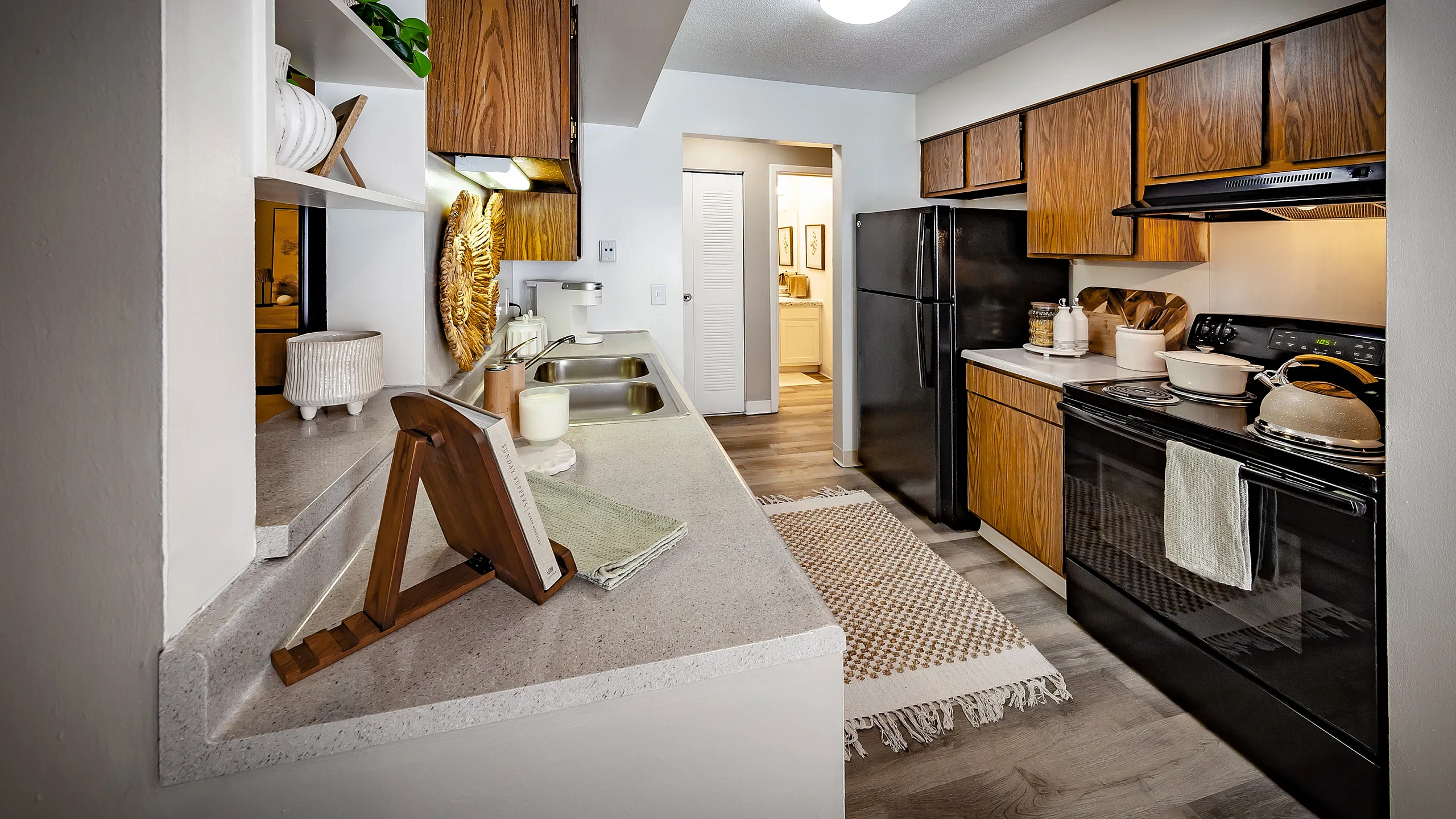 Charming kitchen with sleek countertops, wooden cabinetry, and modern appliances, accented by a cozy rug and decorative accents.