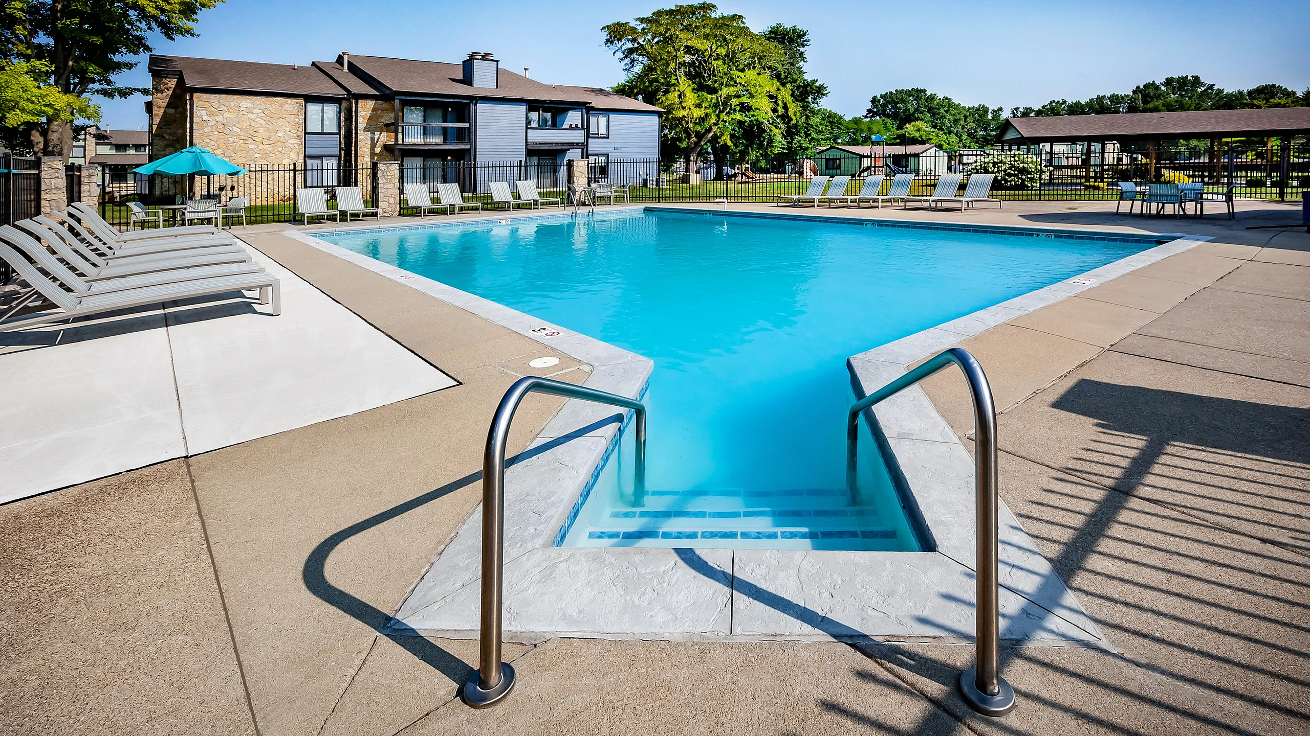 Inviting outdoor pool area with modern loungers and vibrant greenery, providing a perfect relaxing oasis.