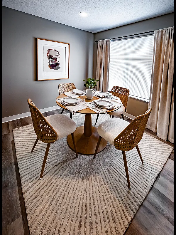Elegant dining area with a stylish round table, cozy wicker chairs, and ambient lighting, perfect for intimate gatherings.