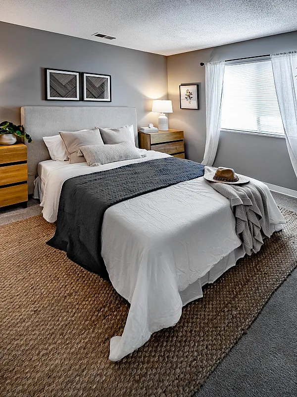 Inviting bedroom with a comfortable bed, stylish wooden dressers, and a cozy reading chair, perfect for relaxation.