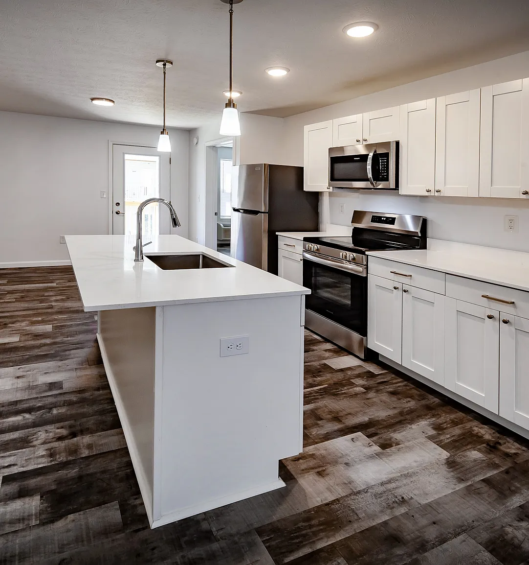 Modern kitchen with elegant white cabinetry, sleek stainless steel appliances, and a spacious island with contemporary lighting.