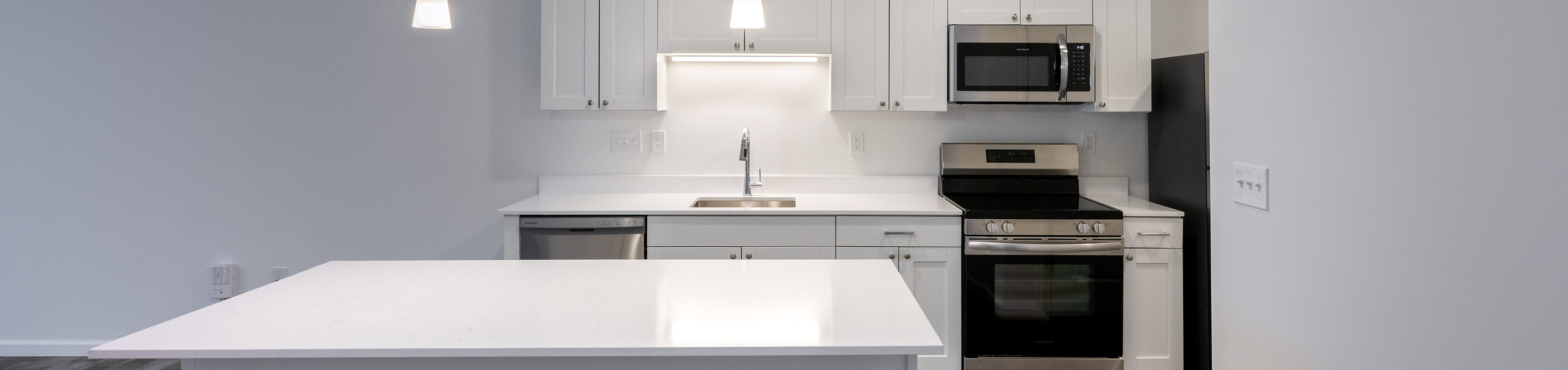 Sleek modern kitchen with a large island, stainless steel appliances, and elegant pendant lighting.