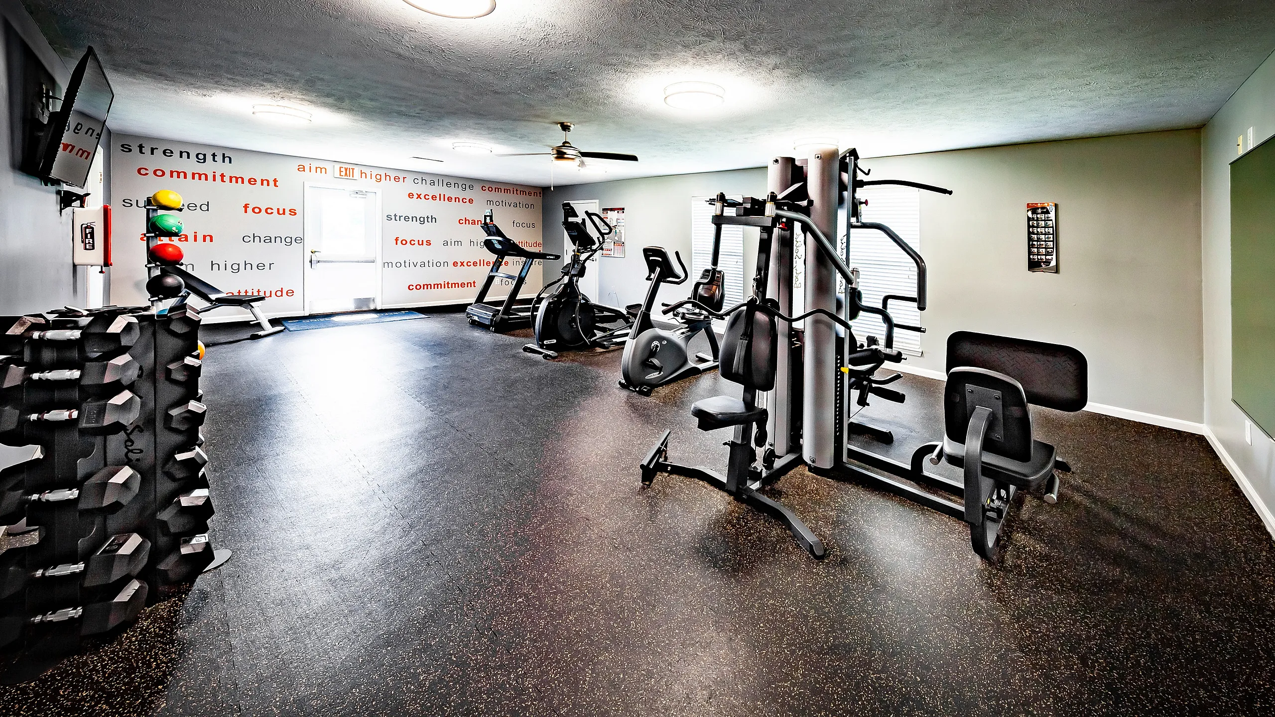 Greenfield Crossing Apartments - Modern fitness center with state-of-the-art gym equipment, vibrant decor, and motivational wall art, perfect for energizing workouts.