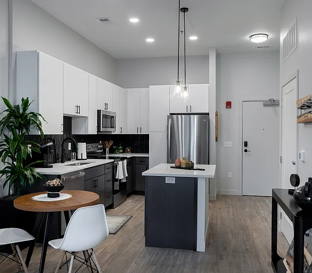 The Elex: Modern open-plan kitchen and dining area featuring sleek cabinetry, stainless steel appliances, and stylish pendant lighting.