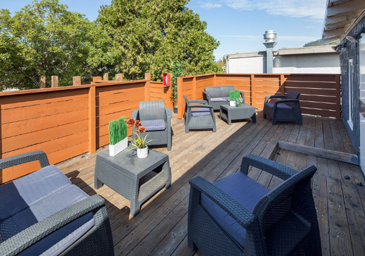 Charming outdoor deck with modern wicker furniture and lush greenery, perfect for relaxation and entertaining.