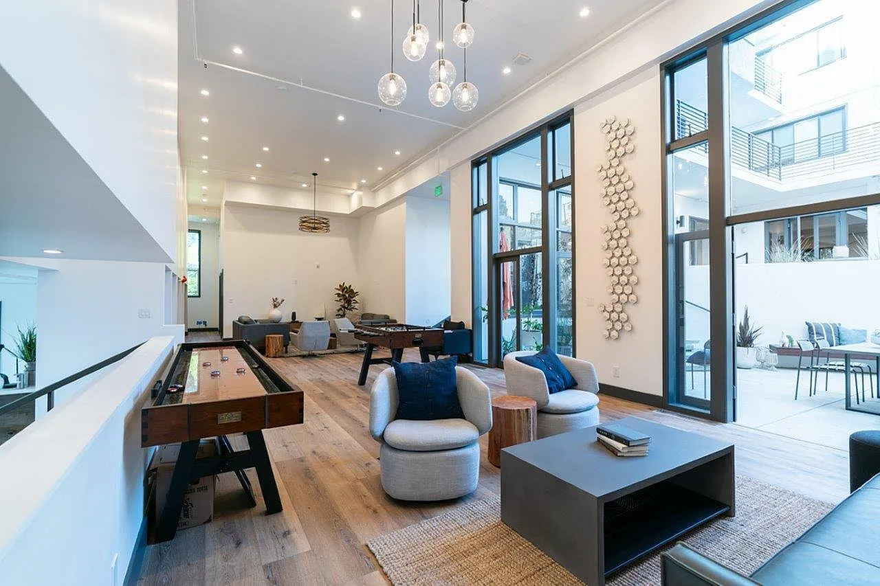 Bright, modern lounge with floor-to-ceiling windows, cozy seating, elegant lighting, and inviting game tables.