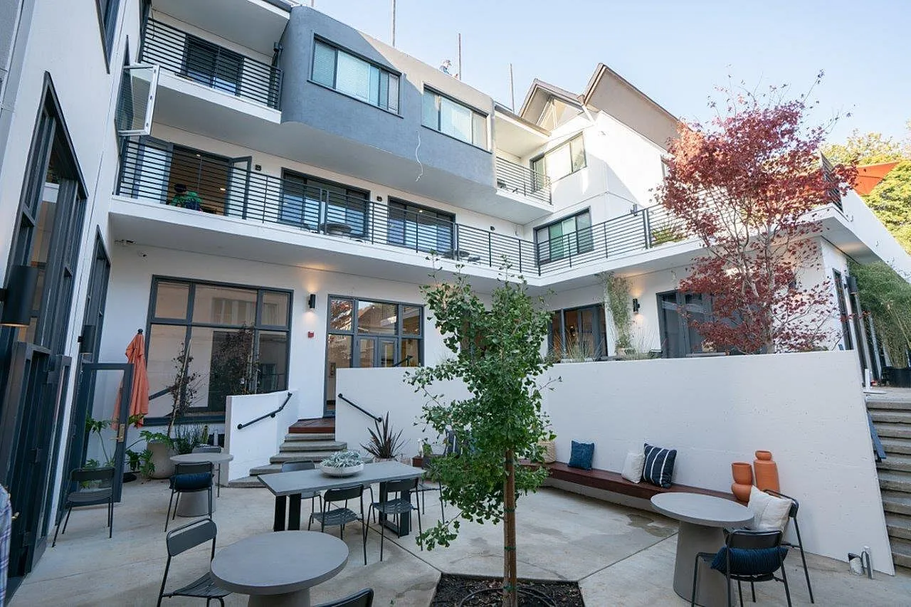 Modern multi-level apartment building with spacious balconies and inviting outdoor seating area.