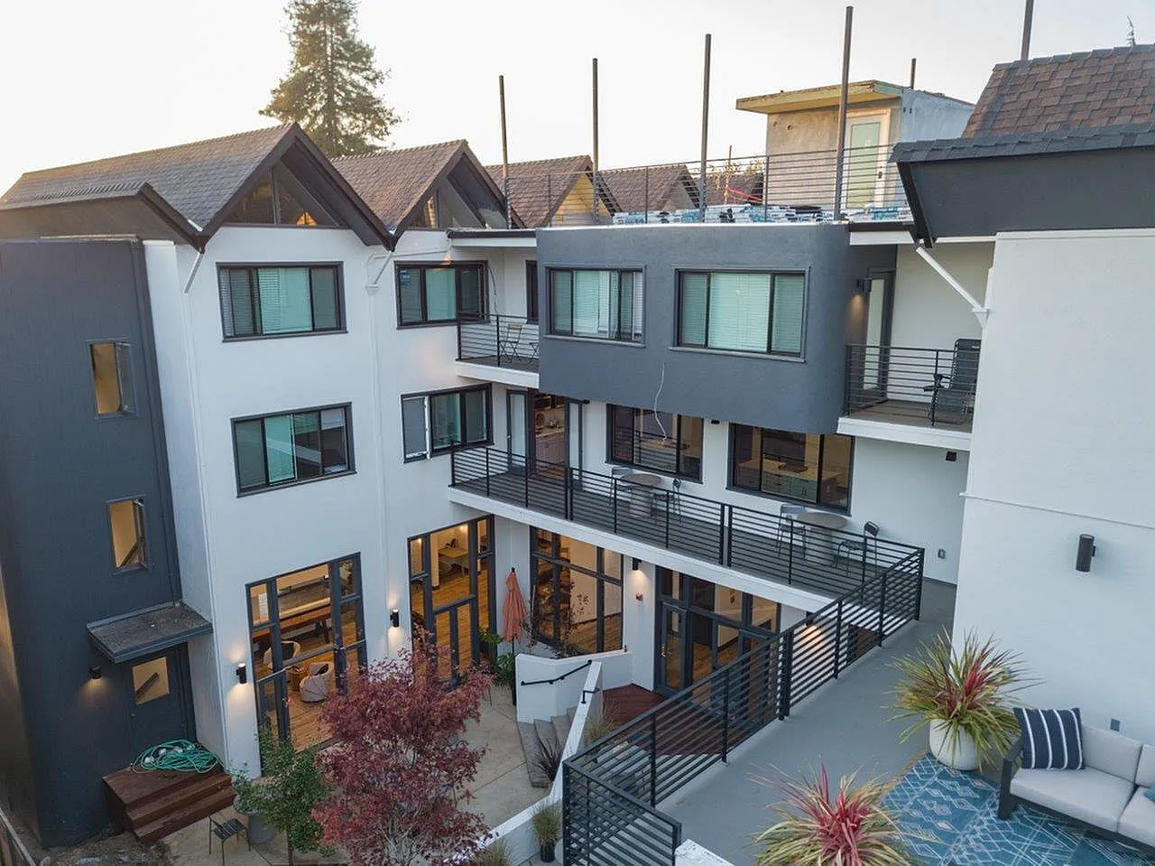 Modern multi-story apartment building with stylish balconies, large windows, and rooftop views, surrounded by lush greenery.