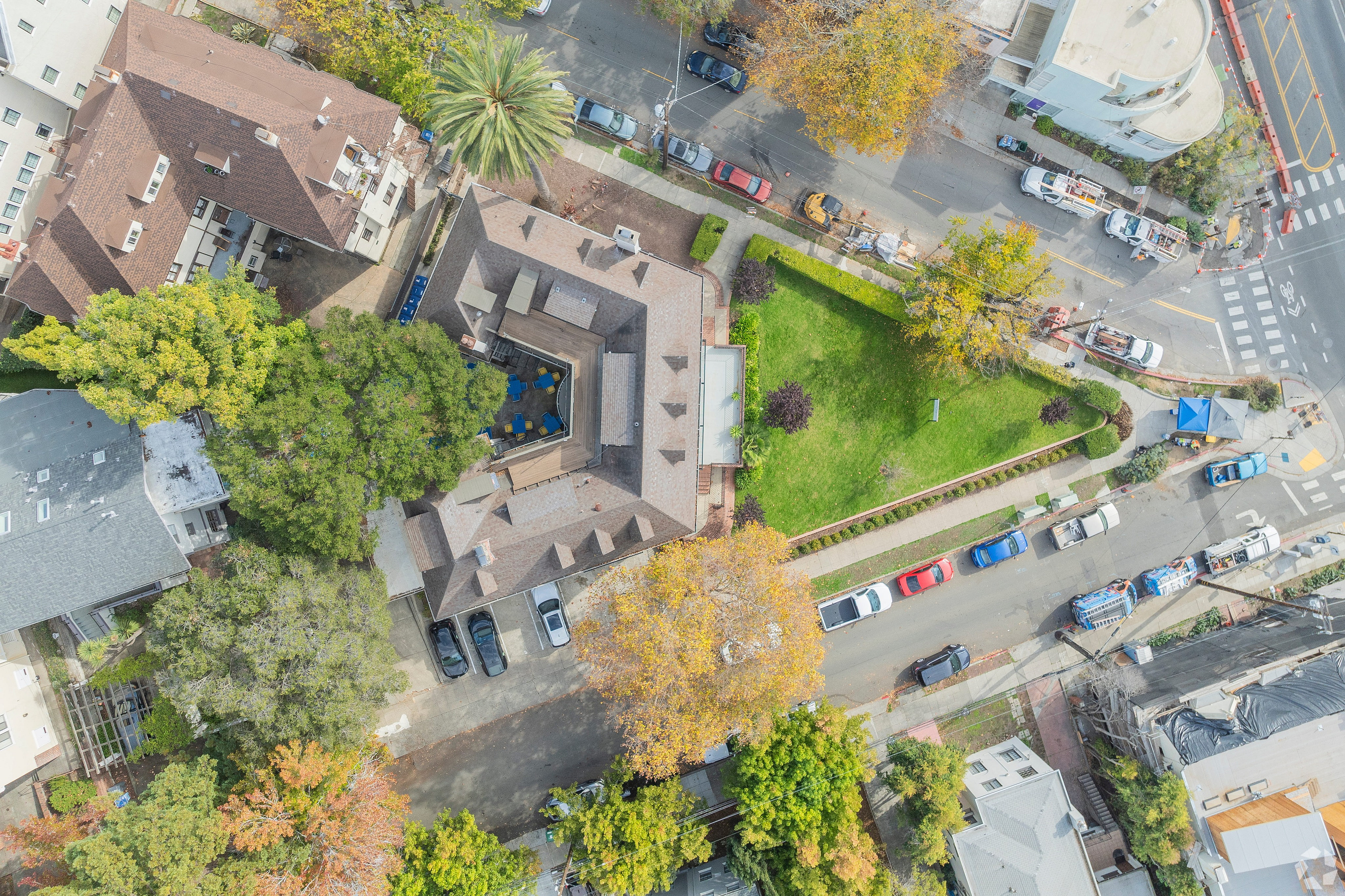 Aerial view of a cozy apartment complex surrounded by lush greenery and a charming neighborhood street.