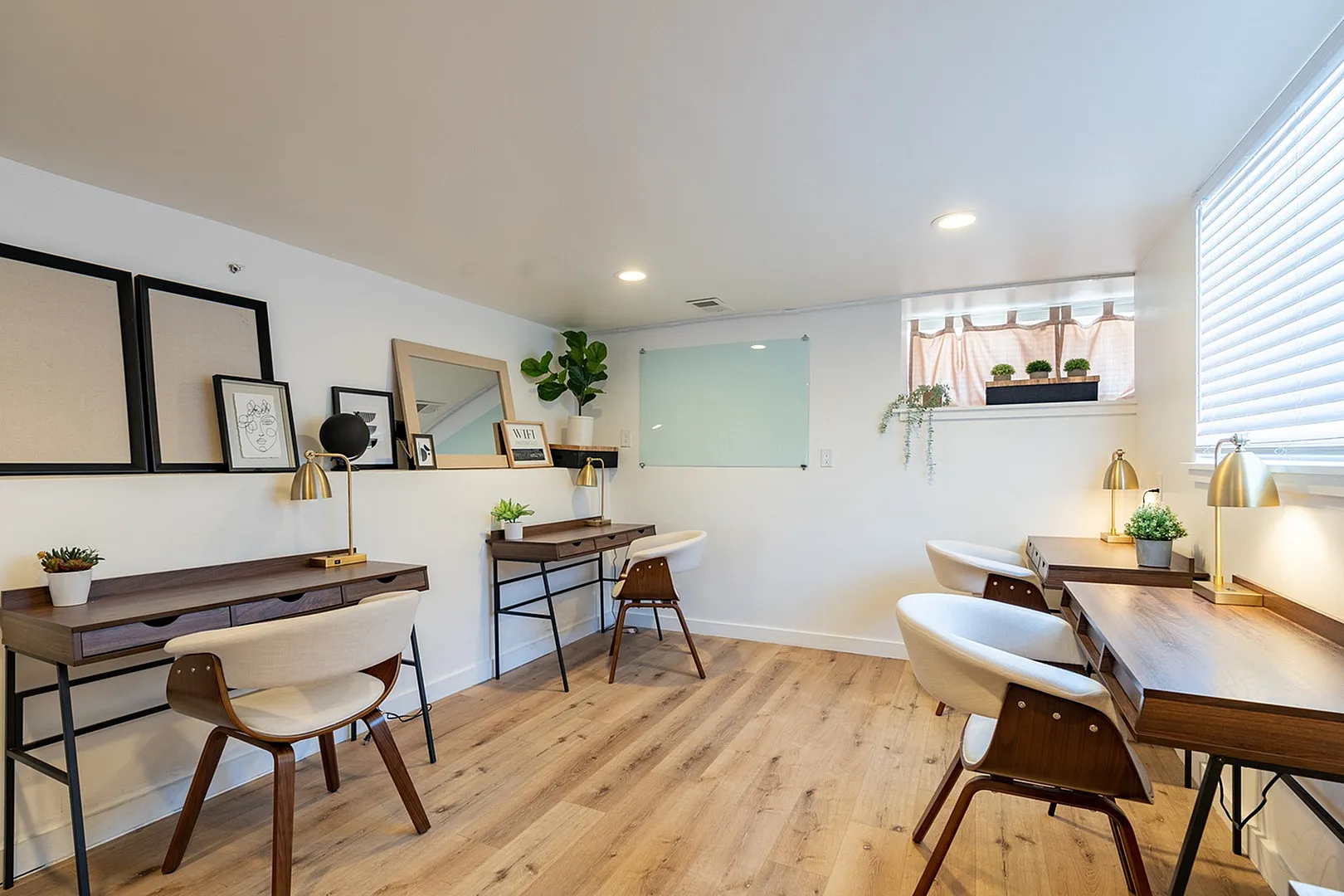 Bright and modern co-working space with stylish desks, chic chairs, and warm lighting, complemented by decorative plants and contemporary art.