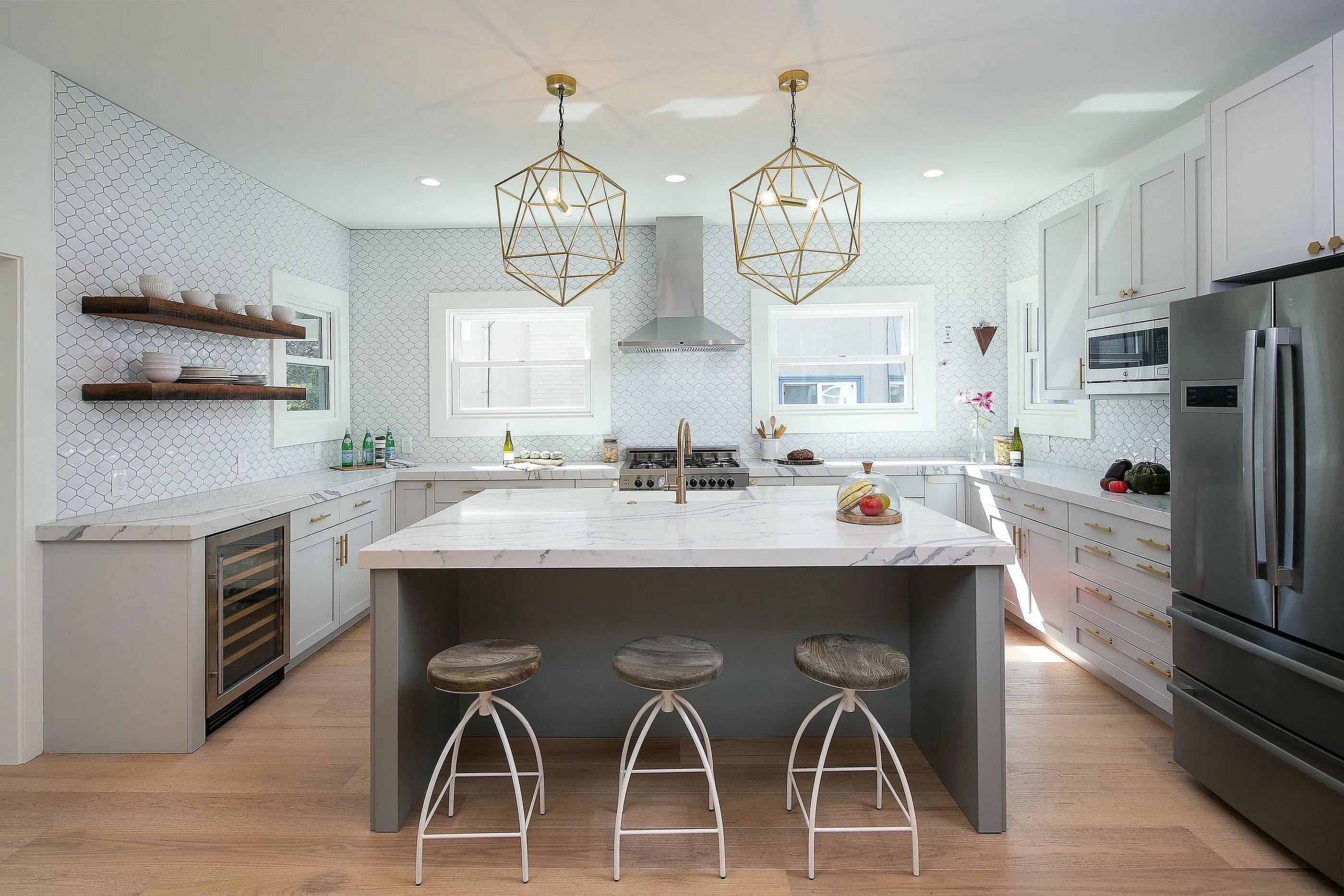 Modern kitchen with elegant marble countertops, sleek stainless steel appliances, and chic pendant lighting, complemented by stylish wooden cabinetry and seating.