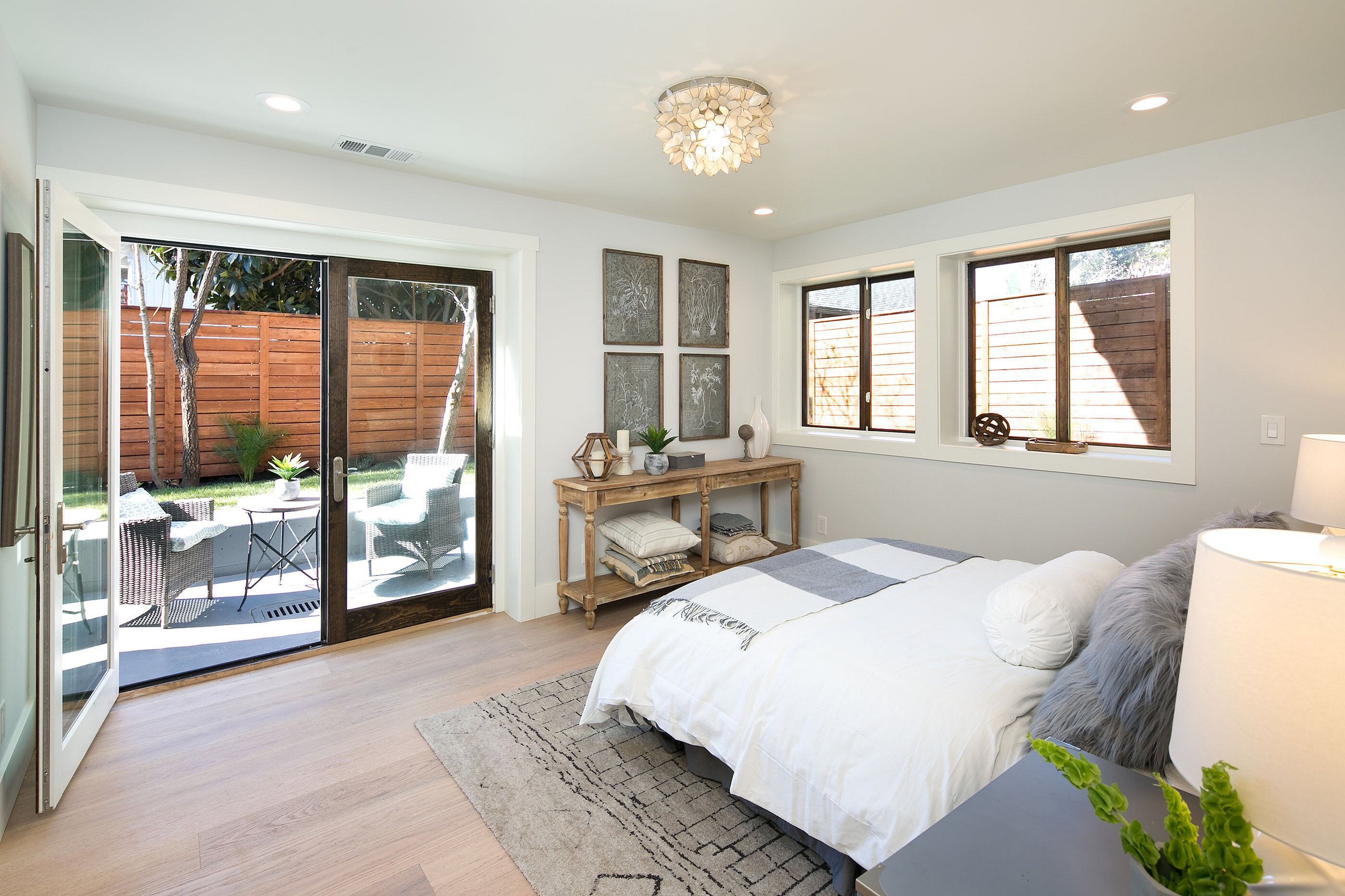 Bright and inviting bedroom with contemporary decor, featuring large windows and glass doors leading to a serene outdoor patio area.