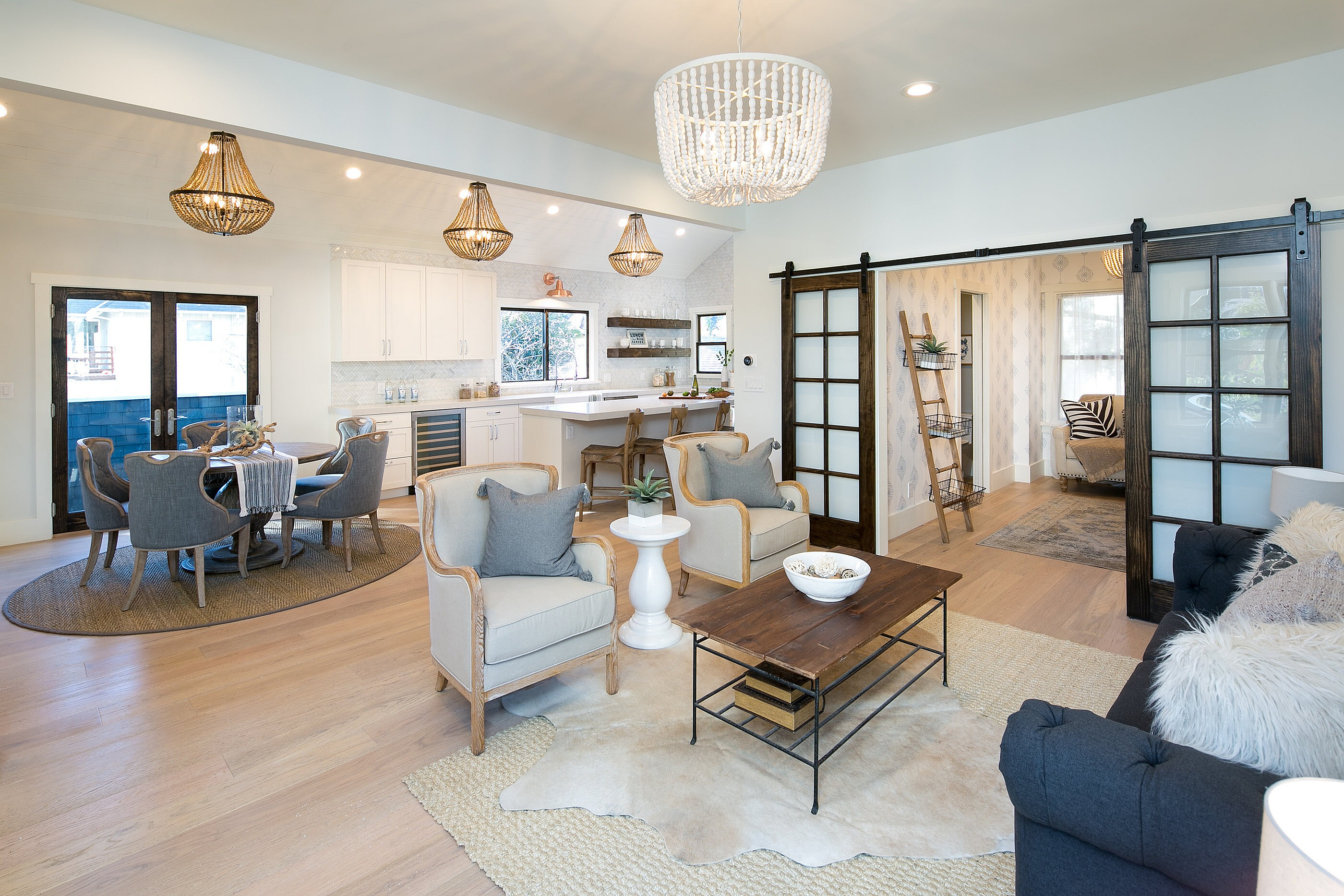 Inviting open-concept living area with elegant lighting, cozy seating, and a modern dining space adjacent to a bright kitchen.