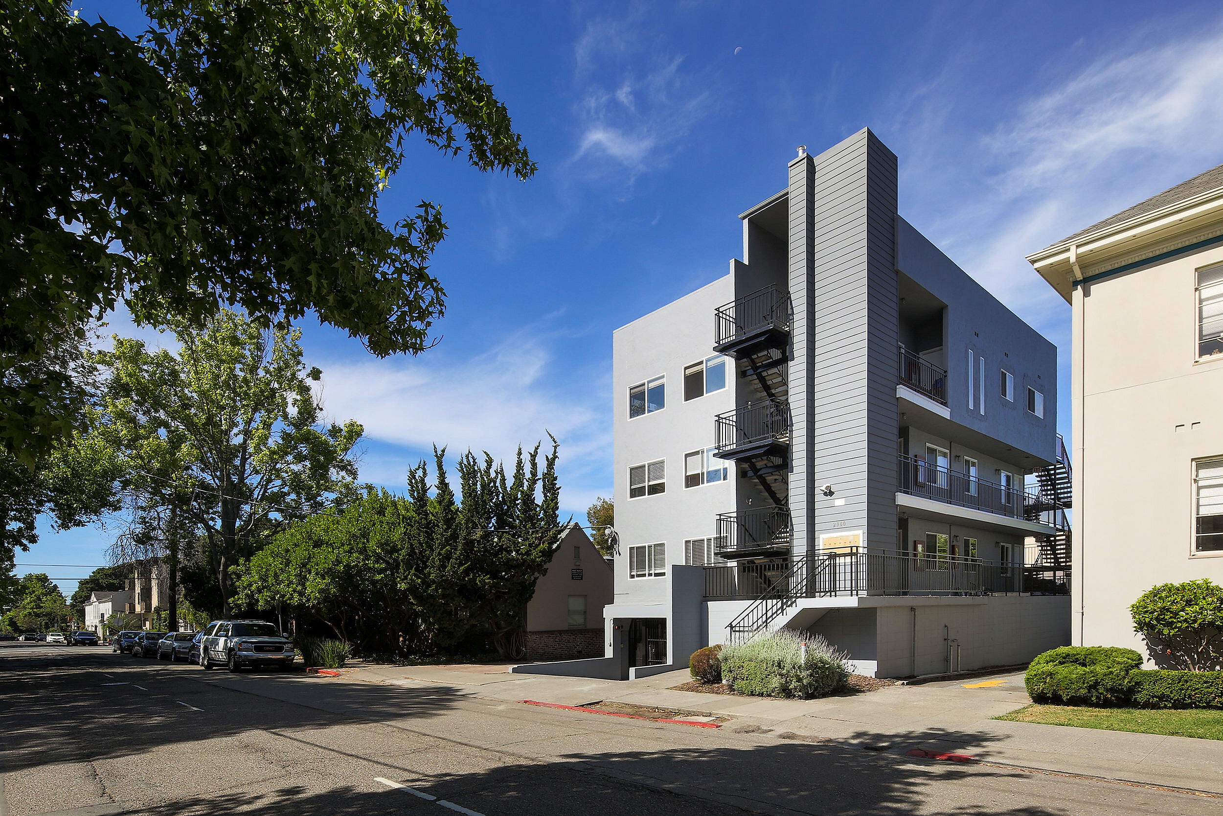 Modern apartment building with stylish exterior and lush greenery on a sunny day.