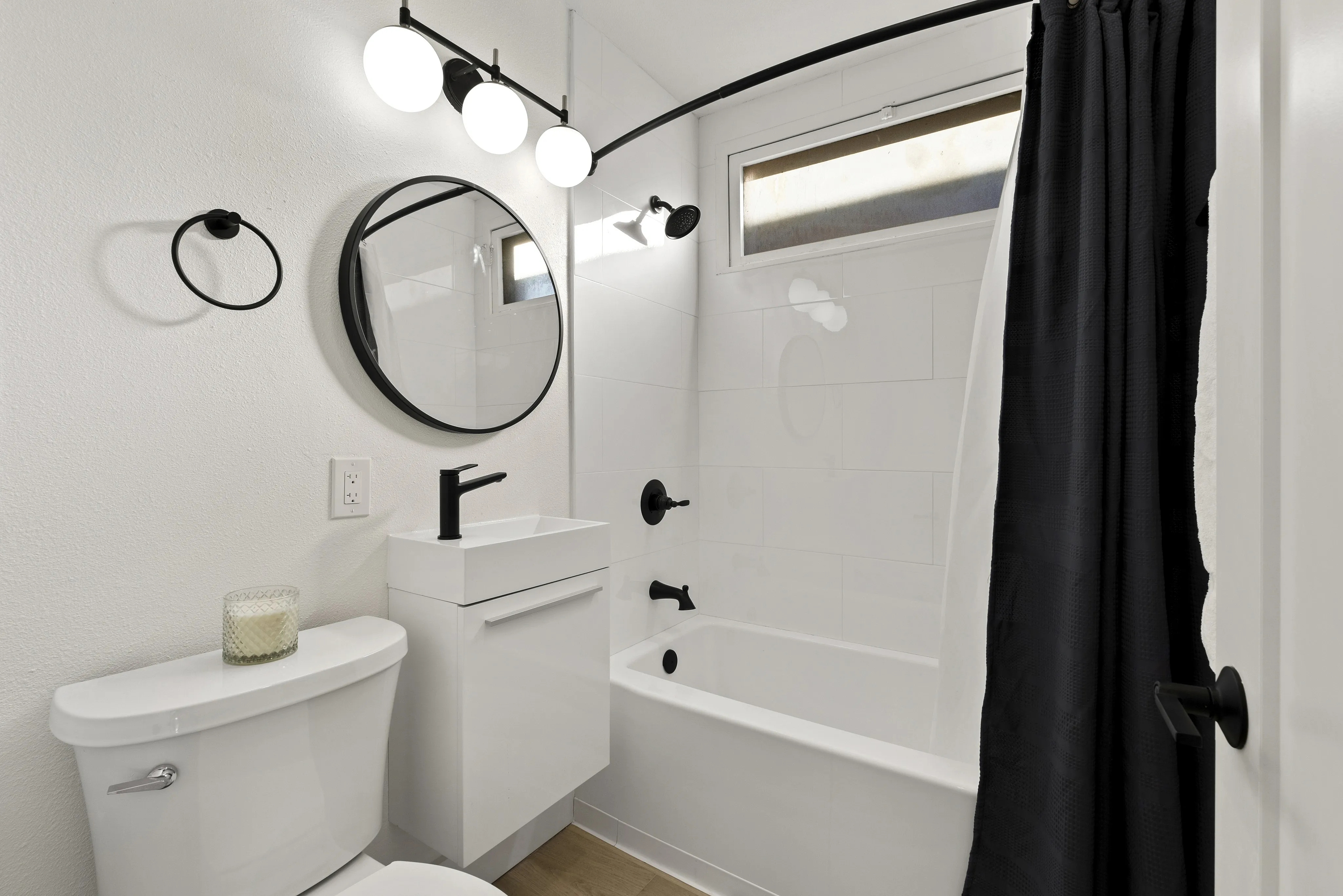 Modern bathroom featuring elegant black fixtures, a stylish round mirror, and a chic black shower curtain.