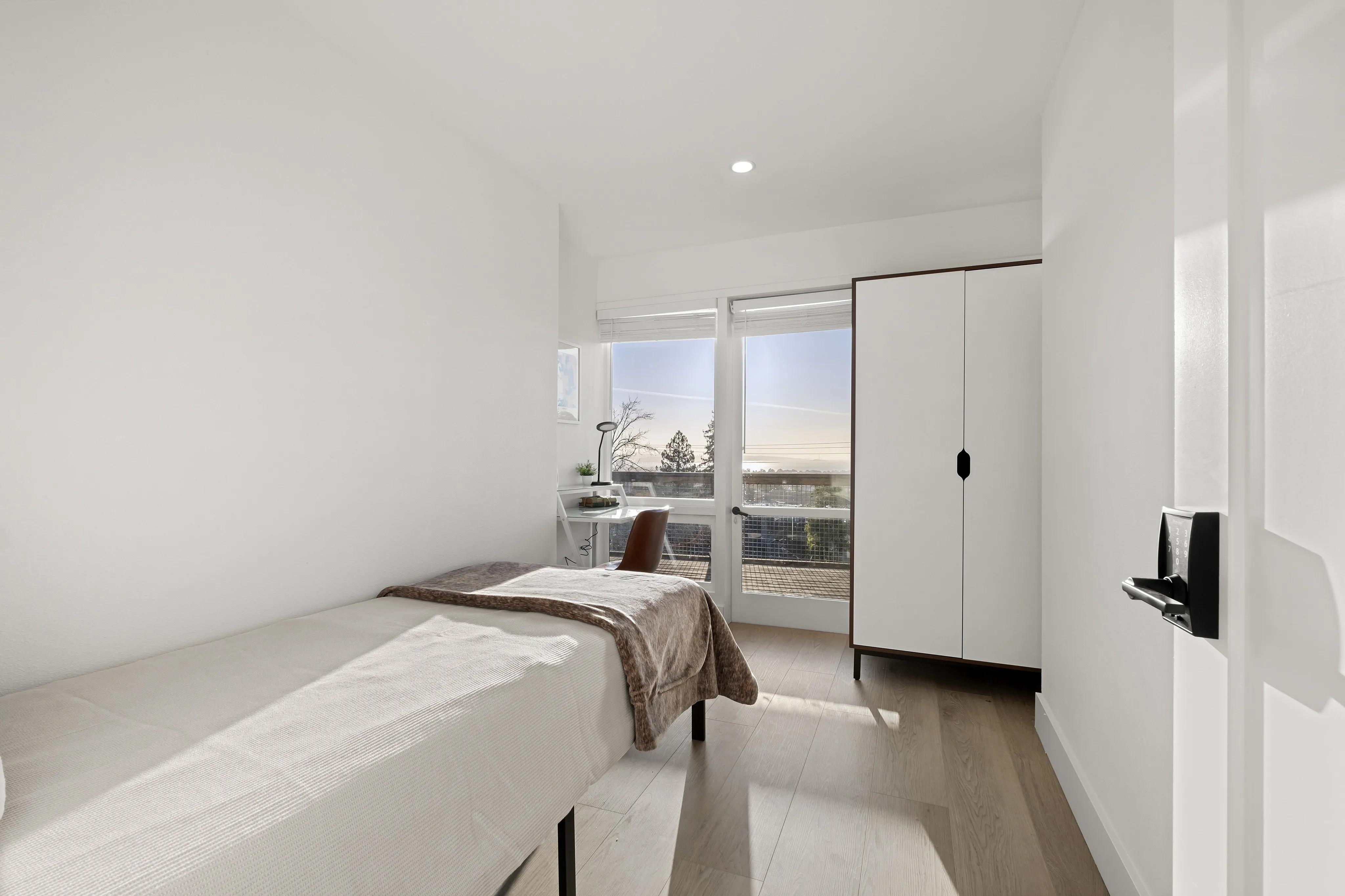 Bright bedroom with chic minimalist decor, featuring a cozy bed, sleek wardrobe, and a serene window view.