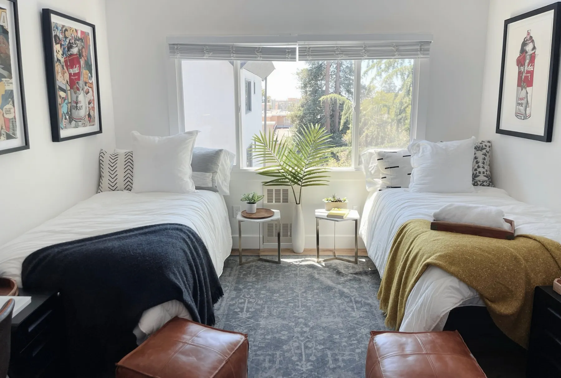 Bright and inviting bedroom with twin beds, stylish decor, and large window offering natural light and scenic views.