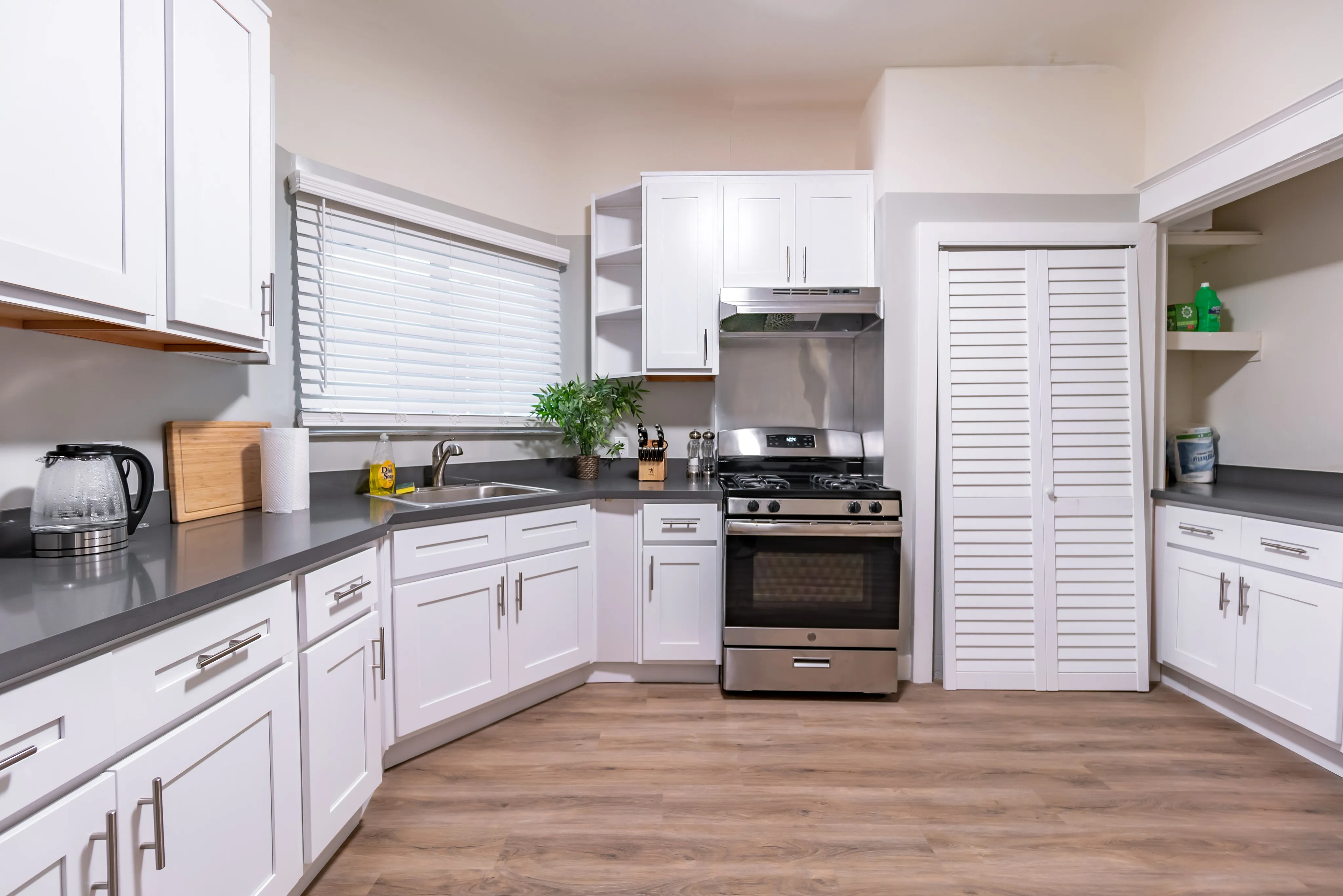 Modern kitchen with sleek white cabinetry, stainless steel appliances, and elegant countertops, featuring natural light and stylish flooring.