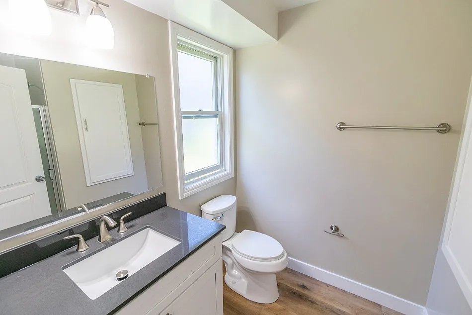 Bright and modern bathroom featuring a sleek vanity, natural light from a large window, and elegant fixtures.