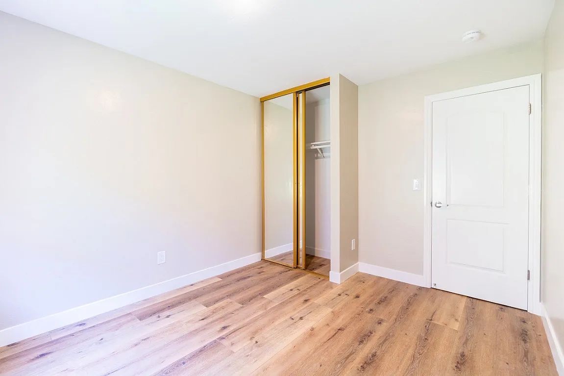 Bright room with hardwood floors and a spacious mirrored closet offering ample storage.