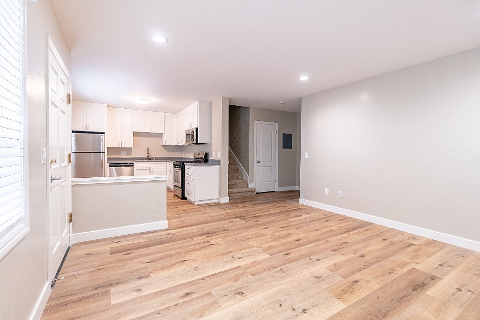 Bright and inviting open-concept space featuring a modern kitchen with stainless steel appliances, hardwood floors, and ample natural light.