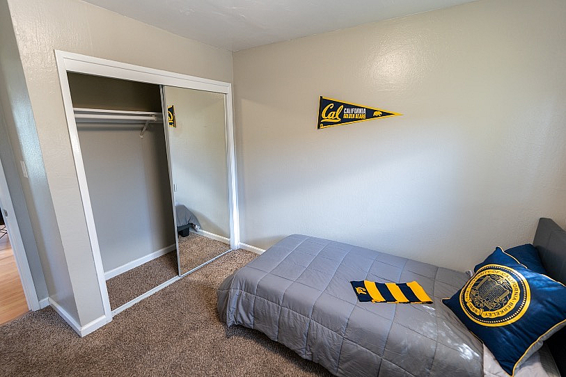 Cozy bedroom featuring a comfortable single bed, mirrored closet doors, and soft carpeting, perfect for relaxation.